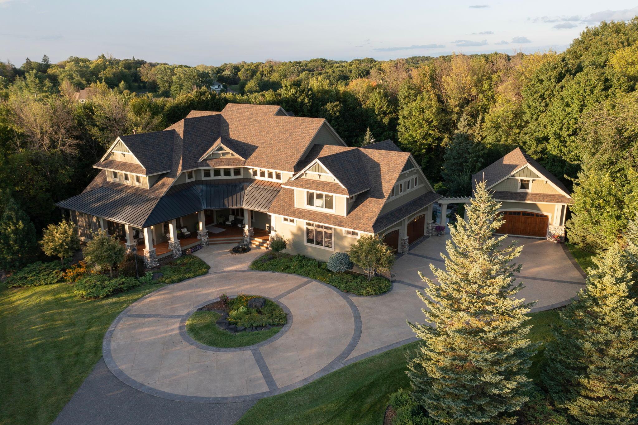 Tucked away on 3.75 breathtaking private acres at the end of a long, winding driveway, this extraordinary custom-built Lundgren estate embodies timeless craftsmanship, elevated luxury, and resort-style living at its finest. Offering over 8,000 finished square feet, the home features 5 bedrooms, 7 bathrooms, and an exceptional level of architectural detail throughout.A striking copper-covered front porch sets the tone for the remarkable design found inside. Rich rustic cherry hardwood floors, soaring 12-foot ceilings, extensive custom millwork, built-ins, and four fireplaces create a warm, sophisticated aesthetic reminiscent of a classic Ralph Lauren estate. Designed to seamlessly balance grand-scale entertaining with comfortable everyday living, the home showcases an exceptional gourmet kitchen, beautifully curated gathering spaces, and an impressive walkout lower level complete with a spacious family room, full custom bar with refrigerator and a remarkable stone wine cave.The home is equally impressive in its thoughtful everyday functionality and luxury conveniences, including both an upper-level laundry room and a secondary main-level laundry near the mudroom. A state-of-the-art, fifteen-zone indoor/outdoor Elan AV system delivers exceptional whole-home audio and entertainment integration, highlighted by a premium Bowers & Wilkins Atmos media room experience.Upstairs, each bedroom enjoys its own private en-suite bath, including the luxurious primary suite featuring a fireplace, spa-inspired bath with oversized walk-in shower and separate soaking tub, expansive walk-in closet, private wet bar with refrigerator and microwave, and its own screened porch creating a true private sanctuary. In total, the home features three screened porches, offering multiple spaces to relax and enjoy the surrounding natural beauty throughout the seasons.Outside, the property transforms into a true private retreat. Resort-caliber amenities include a stunning pool, lower level steam shower, expansive patio and entertaining areas, outdoor kitchen, tranquil koi pond with waterfall, and exquisite professional landscaping that envelops the home in complete privacy and natural beauty.Car collectors, hobbyists, and those seeking additional flexibility will appreciate the attached heated and insulated four-car garage, complemented by a detached finished and insulated two-car garage with unfinished space above offering future expansion potential.A truly rare offering combining unmatched privacy, exceptional craftsmanship, advanced technology, and an elevated lifestyle experience—all ideally located just 10 minutes west of Wayzata with convenient access to the Luce Line Trail, Lake Minnetonka, wineries, dining, and endless surrounding natural beauty.