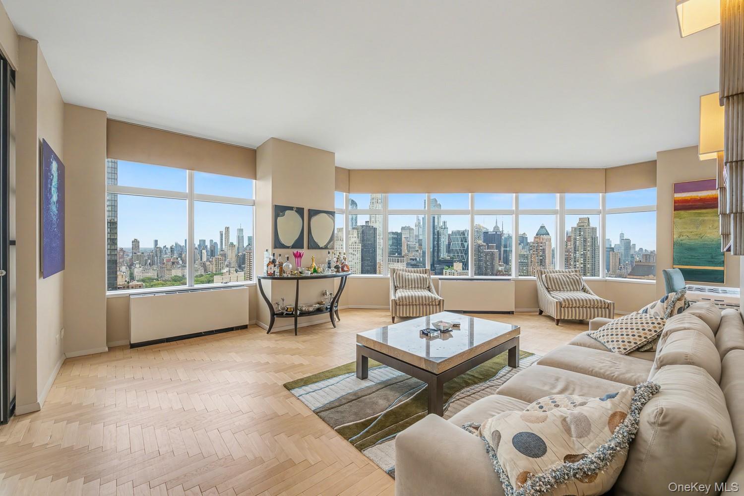 Perched on the 49th floor of the iconic 3 Lincoln Center, this approximately 1,800-square-foot three-bedroom, three-bath residence offers breathtaking panoramic views of Central Park, the Manhattan skyline, and the Hudson River through dramatic floor-to-ceiling corner windows.A gracious entry gallery leads to an expansive living and dining area designed for both comfortable everyday living and large-scale entertaining. Sunlight pours into the home from multiple exposures, highlighting beautiful herringbone hardwood floors and showcasing spectacular city vistas from nearly every room.The windowed dining area is perfectly positioned to enjoy the skyline while entertaining, while the adjacent kitchen features ample cabinetry, generous counter space, a Sub-Zero refrigerator, built-in oven, dishwasher, and excellent storage.The spacious primary suite offers stunning park and city views, custom built-ins, and a beautifully appointed en-suite marble bath featuring a separate glass-enclosed shower and soaking tub. Two additional bedrooms provide flexibility for guests, home offices, or family living, with one currently configured as a den featuring sliding doors that seamlessly connect to the main living area. Additional marble baths complete the home.Located in one of Lincoln Square's premier full-service condominium buildings, residents enjoy white-glove service, a 24-hour doorman, concierge, health club, swimming pool, resident lounge, garage, and direct access to the cultural, dining, and shopping destinations surrounding Lincoln Center, Columbus Circle, Central Park, and the Upper West Side.