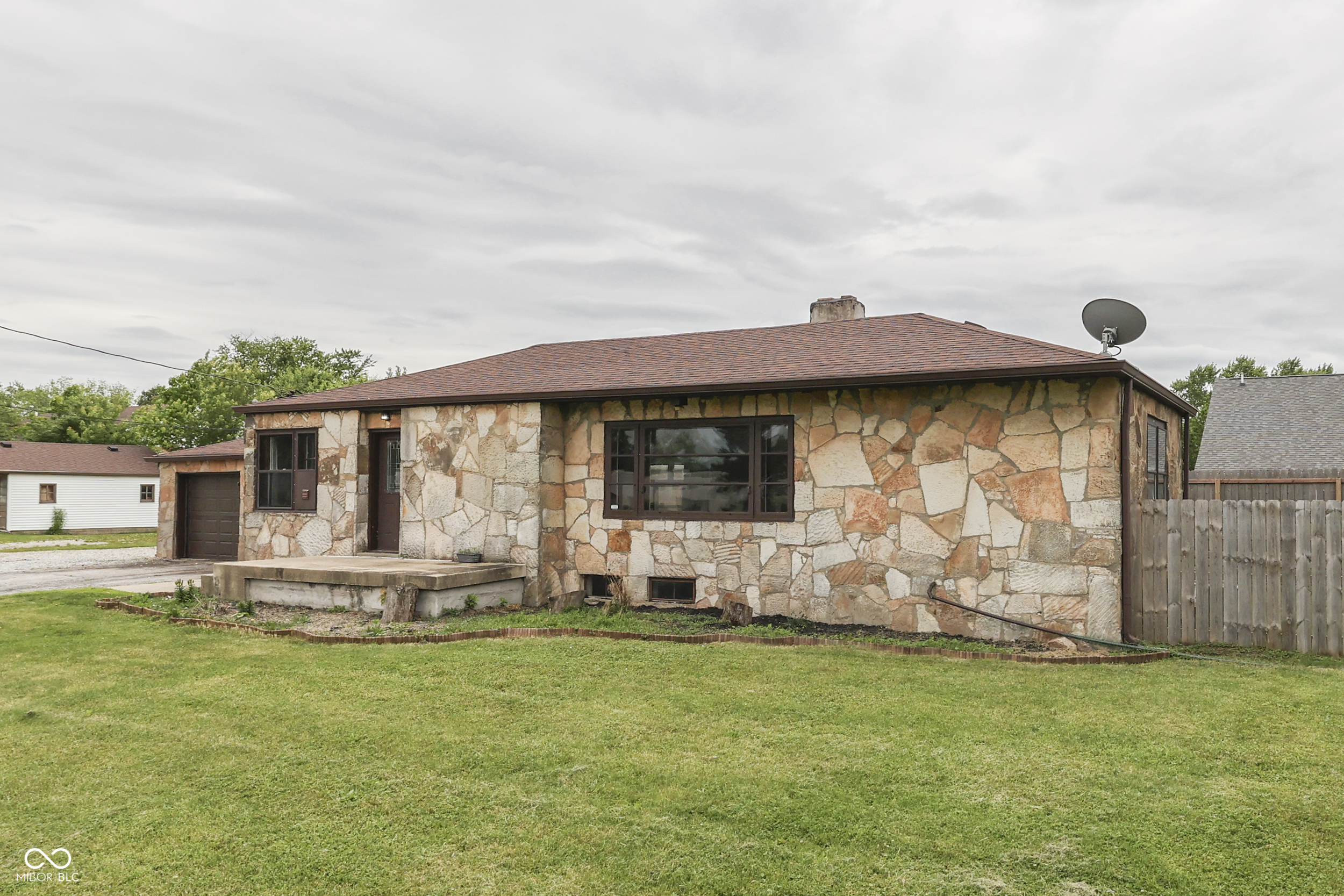 Welcome to a timeless Beech Grove classic where character and comfort blend beautifully. This stone ranch offers nearly 3,000 sq ft of thoughtfully designed living space surrounded by mature trees and a sense of calm that's hard to find so close to the city.    Inside, natural light fills the spacious living room accented by hardwood floors and a cozy gas-starter fireplace - perfect for unwinding after a long day. The kitchen features ample cabinetry and an easy flow into the dining area, creating an inviting space for gatherings. Three comfortable bedrooms and 1.5 baths offer the right balance of space and function, while the full basement provides flexibility for storage, hobbies, or future finishing potential.    Step outside to a glass-enclosed patio overlooking the fenced backyard - ideal for morning coffee, quiet evenings, or entertaining friends. The heated and cooled two-car garage adds extra convenience year-round.    Located near Beech Grove parks, local shops, and community favorites, this home combines small-town charm with quick access to Indianapolis amenities.    A truly special property where comfort, character, and everyday ease come together.