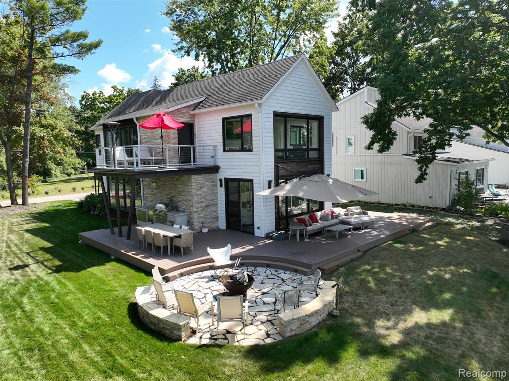 Welcome to an extraordinary lakefront retreat on Zukey Lake, offering 74 feet of pristine, sandy beachfront and direct access to the entire Huron River Chain of 9 Lakes. Custom built in 2021 by the renowned Angelini & Associates Architects of Ann Arbor—featured on the cover of Michigan Blue magazine—this 3,211 sq ft masterpiece blends modern elegance with timeless craftsmanship, delivering an unparalleled living experience. Every detail of this home has been thoughtfully curated to maximize panoramic water views and elevate everyday living. The expansive open-concept floor plan showcases quarter-sawn oak flooring, soaring ceilings, and walls of windows that flood the interior with natural light. The gourmet kitchen is a showpiece, featuring sleek flush white cabinetry, cast concrete aggregate countertops, premium stainless-steel appliances, and a generous island/snack bar that flows seamlessly into the dining area. The great room centers around a striking stacked stone fireplace, flanked by a cozy sitting area and dining space which are all oriented to capture breathtaking lake vistas. Step through the door walls to an entertainer’s dream: a spacious composite deck with a full outdoor kitchen, built-in BBQ, refrigerator, circular firepit and multiple seating areas designed for relaxation and gatherings. The lakeside primary suite is a sanctuary unto itself, complete with a private balcony for sunset views, a luxurious California walk-in closet with dressing area, and a spa-inspired bath featuring dual sinks, a tiled walk-in shower, and elegant finishes. Two additional bedrooms offer generous proportions, while a main-floor office adjacent to a full bath provides flexible space for a potential 4th bedroom. Located just steps from the Lakeland Trail, this property invites an active lifestyle—perfect for biking, running, or walking. Sewer assessment is paid in full; paved road assessment to be assumed by purchaser.  This is more than a home—it’s a year-round vacation!