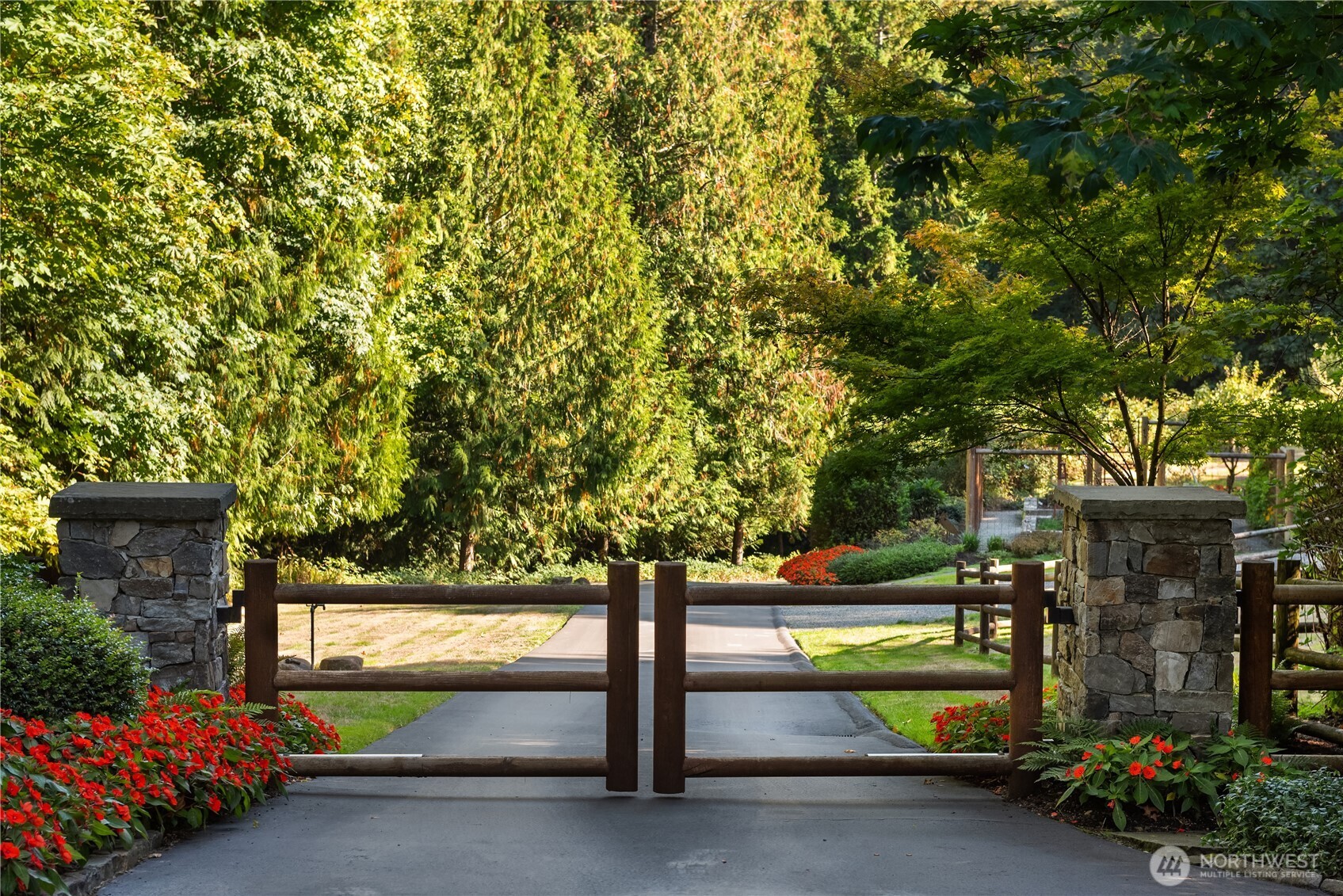 Wood entry gate with stone pillars and tree-lined driveway
