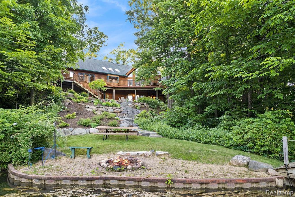 Imagine owning this extraordinary luxury log cabin home, nestled in a breathtaking setting with the soothing sounds of a waterfall, unfolding as a serene oasis. With its expansive property spanning almost six acres, complete with a large pond, this haven offers a tranquil and private environment for nature enthusiasts to unwind and recharge. As you enter this magnificent home, you are greeted by a two-story great room with an abundance of windows, offering awe-inspiring views that evoke a deep sense of relaxation, serenity, and tranquility. A grand staircase contributes to the airy and open feel of the home, leading to the upper level, where dreams, aspirations, and limitless possibilities come alive. The main kitchen is a gourmet chef's dream, boasting ample counter space and elegant cabinetry, making it perfect for meal preparation, hosting guests with flair and finesse, and creating unforgettable culinary experiences. This luxurious log cabin features 3 spacious beds 2 on lower level,  each designed with comfort, style, and inspiration in mind. The primary bedroom is a true retreat, featuring a lavish en-suite bathroom. The finished lower level of this home is an entertainer's paradise, complete with a second kitchen, ideal for hosting gatherings, accommodating guests with ease and warmth, and creating lasting memories. Walkout access leads to a beautifully landscaped backyard, offering picturesque views of the water, inviting outdoor exploration, adventure, and a profound connection with nature. This home was built by Gastineau Log Homes, a once-in-a-lifetime kind of find, crafted with stunning Oak wood that adds timeless beauty and unmatched character. A MUST SEE!!