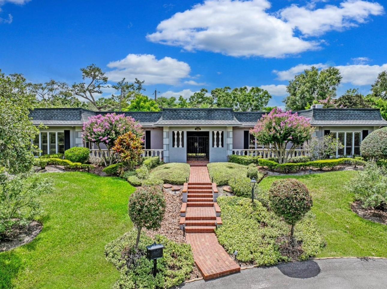 Enjoy worry-free living and elevated entertaining in this French-inspired estate, featuring a whole-home generator and a completely remodeled, show-stopping Chef's Kitchen —perfectly suited for Florida living. Tucked away on a quiet cul-de-sac in the highly desirable Scott Lake area, this exceptional residence offers deeded lake access and scenic lake views from select areas of the home, blending privacy, elegance, and lifestyle.A stately brick walkway, lush landscaping, and classic brick terraces create a striking first impression. Through grand double doors, the home reveals a refined showcase of craftsmanship with plantation shutters, custom millwork, and architectural detail throughout. This thoughtfully designed 4-bedroom, 3.5-bath residence balances timeless character with modern upgrades.The marble-tiled foyer with grasscloth wallpaper sets a rich, welcoming tone, leading to a charming step-down entertaining space and formal dining room accented by leaded-glass windows. Brazilian cherry hardwood floors, crown molding, and soft neutral tones enhance the open-concept living areas, all anchored by the fully remodeled chef’s kitchen. Designed for both daily enjoyment and elevated entertaining, the kitchen features an oversized quartz waterfall island, two-tone custom cabinetry, and a concealed custom pantry, complemented by a curated suite of premium appliances by Sub-Zero, Thermador, Bosch, and Rangemaster. A butler’s pantry with a second Sub-Zero refrigerator further enhances functionality and hosting ease.The primary suite offers a peaceful retreat with serene lake views, a spacious walk-in closet, and a beautifully updated spa-style bath. Additional bedrooms include en-suite bathrooms, while a flexible fourth bedroom is ideal for guests or a home office.Outdoor living truly shines on the screen-enclosed swimming pool and lanai, providing a private, low-maintenance setting ideal for year-round enjoyment and entertaining. The sparkling heated saltwater pool creates a tranquil retreat for relaxing or hosting in comfort and privacy. With two new A/C units and the whole-home generator, this home delivers confidence, comfort, and peace of mind in every season.Homes of this caliber—offering architectural character, modern systems, and deeded lake access in such a private setting—are seldom available. This is a home that must be experienced in person. Schedule your private showing today and discover the lifestyle this Scott Lake estate provides.