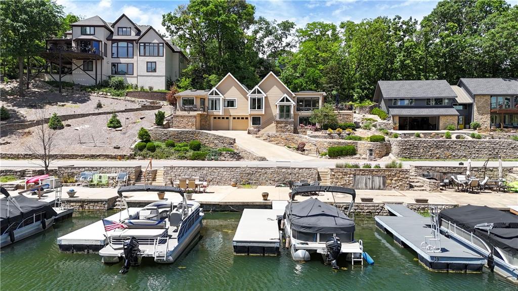 Welcome home to 140 Lakeshore Drive West in Lake Quivira! This home has gorgeous lake views of the first cove and main channel. Directly across the street from the house, a newer dock awaits for your water adventures. The exterior of the house has extensive landscaping and a heated garage. The living room has a windmill-style ceiling fan, a vaulted ceiling, updated floors, a fireplace, and neutral paint. A great sunroom with tons of natural light, a skylight, and gorgeous views of the lake adjoins the living room. The dining area also has lake views- and is conveniently located next to the kitchen. The kitchen has a HUGE island, granite countertops, a custom tile backsplash, a large pantry and stainless steel appliances. There is a bonus den/sitting area next to the kitchen. The main level features three full bathrooms and three bedrooms- as well as a laundry room. The house's original primary bedroom has an en-suite bathroom, large closet, and lake views. An addition was added years ago for the current primary suite. The primary suite has a large bathroom with a free-standing tub, a walk-in steam shower with custom tile and a bench, a double vanity, and great views of the back of the lot while still offering privacy. The primary bedroom has a large walk-in closet, a secondary closet, built-in cabinetry, an office area, and an attached deck with lake views. The finished lower level has a full bathroom, multiple living spaces, a fireplace, tile floors and tons of storage. You will love the outdoor spaces- including a huge deck wrapping around two sides of the house. Huge bonus- the house has a heated driveway and newer roof. Incredible opportunity to call this lakefront property your home. Call today!