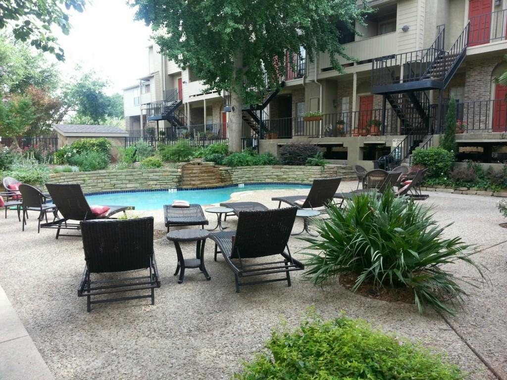 Beautifully located near Greenville Ave, SMU, and Mockingbird Ln, this 2-bed, 2-bath condo offers comfort, convenience, and gated privacy in the heart of East Dallas. Set within a secure community with a pool and eating table, this home includes two assigned underground parking spaces — a rare perk in this area.Inside, the living room feels warm and inviting with wood floors, a freshly painted wood-burning fireplace, a wet bar, and access to one of two private outdoor spaces. The kitchen features stainless steel appliances, an electric range, and a breakfast bar that opens to the living area, creating an easy flow for everyday living.Both bedrooms are tucked along the left side of the home for added privacy, each offering two closets and convenient access to their own full bath. The primary suite enjoys a covered patio overlooking the street — a quiet spot for morning coffee or evening unwinding.Additional highlights include tile flooring in the kitchen and baths, carpeted bedrooms, washer and dryer included, and HOA-covered water, sewer, and trash. With restaurants, nightlife, and shopping on Greenville Ave just a short walk away — plus quick access to Hwy 75 — this location delivers the best of East Dallas living.  Washer and dryer INCLUDED. Owner pays HOA which covers water, sewer and trash.  Assigned underground parking spaces are #23 and #24.