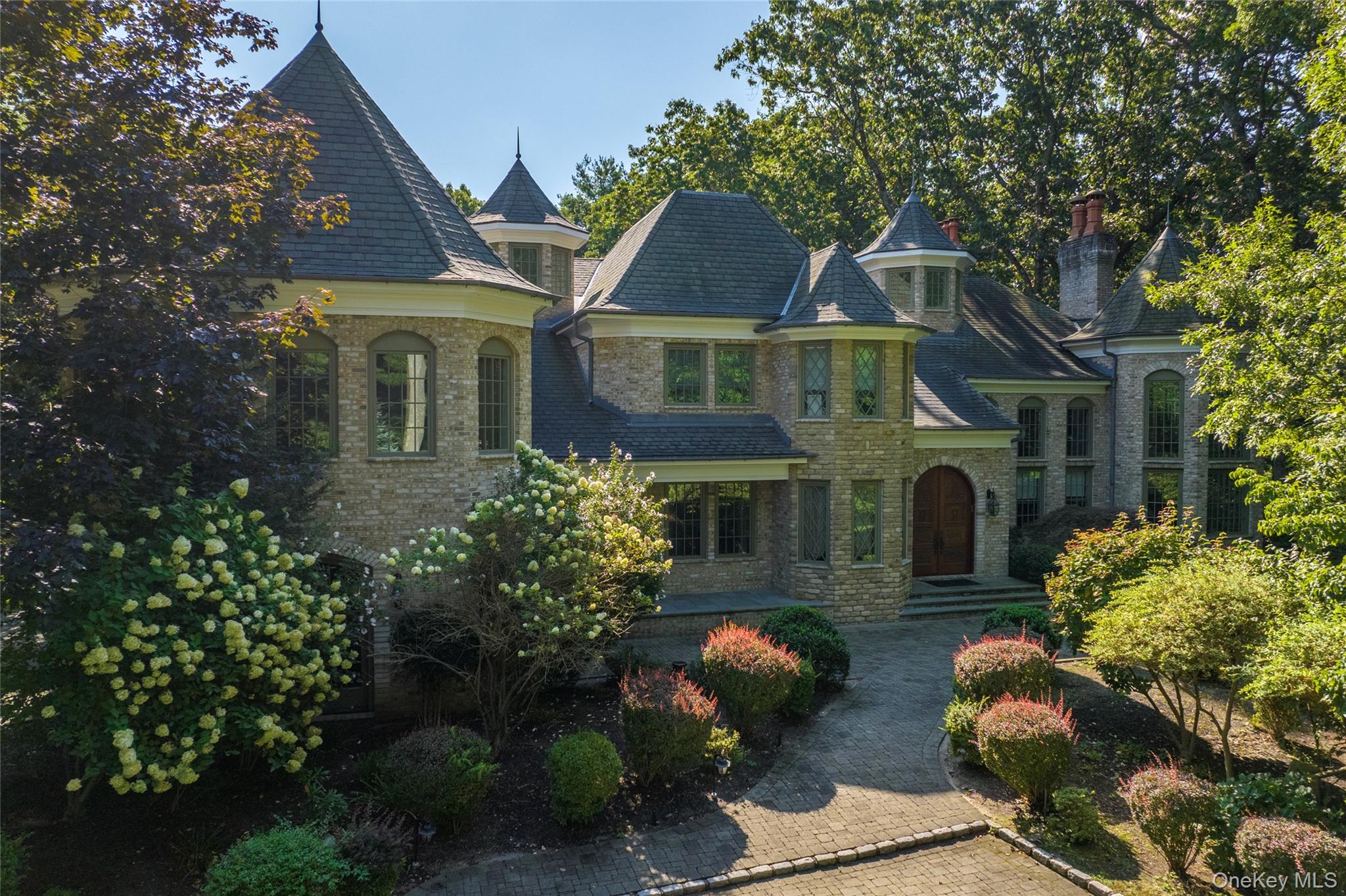 Timeless Elegance in the Heart of Muttontown.  Set along a long, gated private drive in coveted Muttontown, this distinguished six-bedroom Brick Colonial offers an extraordinary blend of classic architecture and modern sophistication. Every detail of this grand residence reflects masterful craftsmanship—custom millwork, rich hardwood floors, designer finishes and five fireplaces create an atmosphere of refined luxury throughout.
A dramatic two-story foyer with a sweeping staircase introduces interiors of impressive scale and symmetry. The state-of-the-art kitchen, outfitted with top-tier appliances, opens seamlessly to a sunlit den for effortless daily living and casual entertaining. A glass-wrapped conservatory bathes the home in natural light, while the elegant living room with built-in bar and the baronial dining room set the stage for memorable gatherings. Additional spaces include a distinguished home office, an inviting billiard room and home theater.  The sumptuous primary suite offers a private sanctuary with a study, expansive dressing room, and spa-caliber marble bath. The lower level is designed for leisure and entertainment.  Nestled on a serene and picturesque 2.79-acre setting, the property is graced with mature specimen plantings, a sparkling in-ground pool and a charming pool house—perfect for outdoor entertaining and relaxed summer living. A four-car garage and whole-house generator complete this exceptional offering.  Experience timeless elegance and modern comfort in one of Long Island’s most prestigious communities.