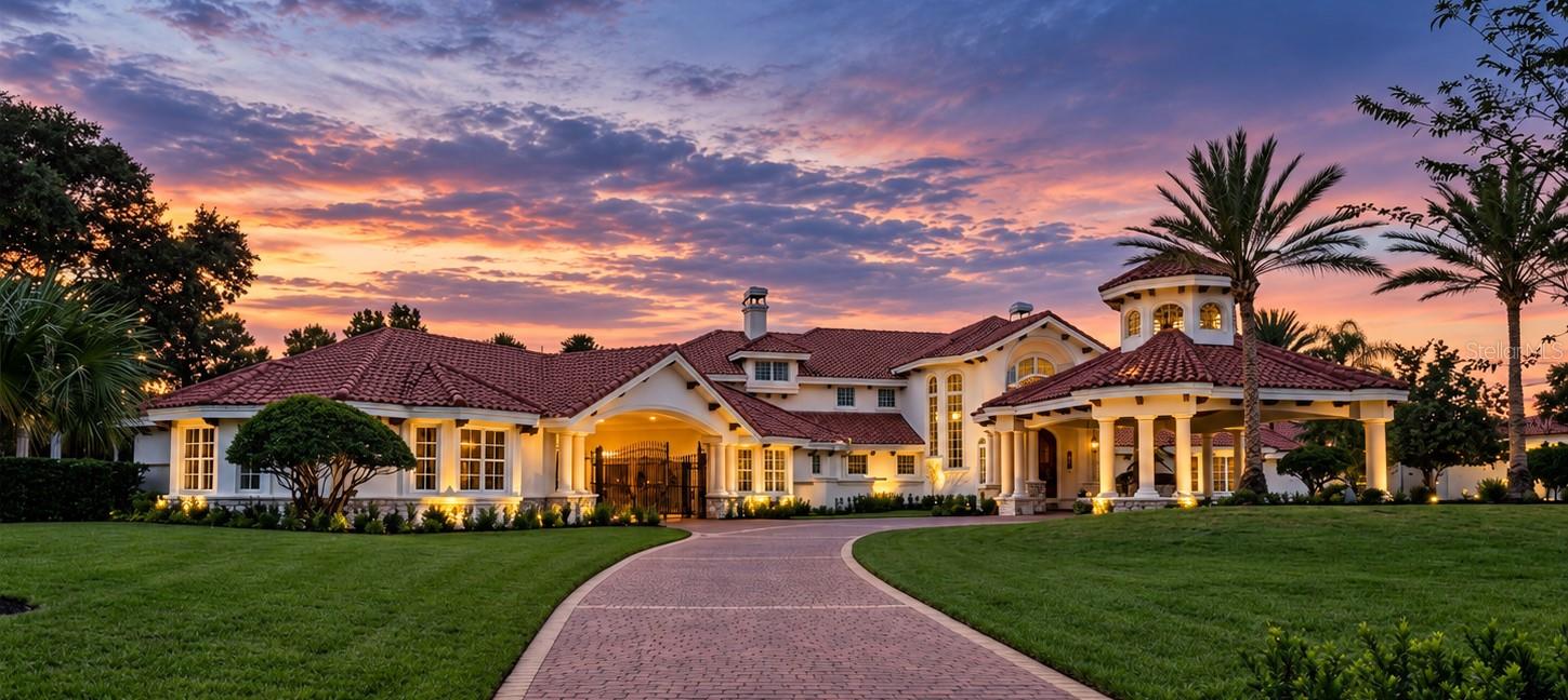 Alaqua's flagship estate: an unparalleled custom residence set on a rare 2.31-acre double homesite, the widest within Seminole County's premier luxury neighborhood, the 24-hour guard-gated community of Alaqua. Surrounded by sweeping golf course, conservation, and water views, this remarkable property offers an extraordinary combination of privacy, scale, architectural presence, and resort-style living. A stately porte-cochère creates an impressive arrival and introduces an interior defined by soaring ceilings, intricate millwork, abundant natural light, and a dramatic grand dual staircase. At the heart of the residence, the formal living room makes a striking statement with coffered 23' ceilings, expansive two-level windows taking advantage of vistas behind, custom built-ins, and an elegant fireplace. Generous proportions and a seamless connection to the surrounding living spaces make the home equally suited for intimate gatherings and grand-scale entertaining. The gourmet kitchen is designed for both beauty and function, featuring premium appliances, extensive custom cabinetry, and an oversized center island with abundant workspace and seating. Opening directly to the spacious family room, the kitchen creates an inviting environment for everyday living while maintaining the sophistication expected of an estate of this caliber. A gracious formal dining room provides an elegant setting for memorable dinners and special occasions. The upper-level primary suite is a private retreat unto itself, showcasing picturesque golf and water views along with beautifully designed custom walk-in closets. The spa-inspired bath features dual vanities, polished marble finishes, an oversized frameless-glass shower, and a freestanding soaking tub. A private kitchenette and dedicated laundry further enhance the suite’s exceptional comfort and convenience. Adjacent to the primary suite, a distinctive glass-enclosed room overlooks the dramatic living space below and offers remarkable versatility as a private office, fitness studio, sitting room, or additional retreat. Multiple ensuite bedrooms provide privacy and comfort for family and guests, while a dedicated theater is designed for an immersive entertainment experience, featuring custom wood detailing, cove lighting, a convenient minibar, surround sound, and a sophisticated cinematic atmosphere. Outdoors, the estate transforms into a private resort. The expansive pool and raised spa are complemented by dramatic water features and lush tropical landscaping, creating an atmosphere of serenity and seclusion. A fully equipped outdoor kitchen with built-in grill, hood, generous preparation areas, and service space makes year-round entertaining effortless. Expansive pool decking provides abundant room for lounging and entertaining, while the covered lanai—with decorative beams and multiple ceiling fans—offers a sophisticated extension of the home’s interior living spaces. Beyond, panoramic golf course and water views create a spectacular backdrop from morning through evening. From quiet mornings overlooking the water to unforgettable gatherings beneath the covered lanai, 2405 Alaqua Drive represents a rare opportunity to own a truly exceptional estate on one of Alaqua’s most distinctive double homesites.  This property may be under audio/visual surveillance.