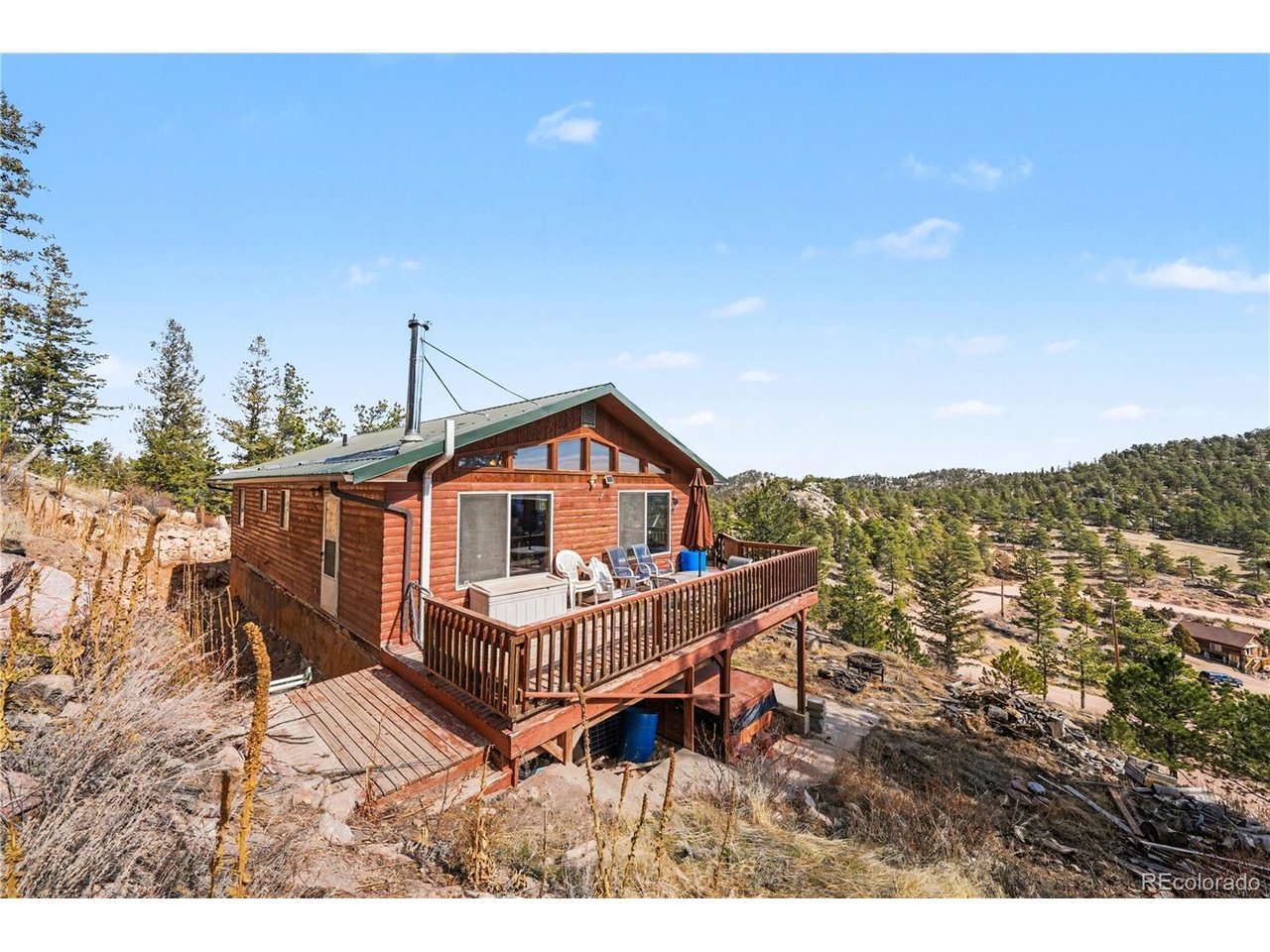 Escape to the heart of the Red Feather Highlands and discover a mountain home that perfectly balances tranquility with true Colorado lifestyle. This residence offers the best of mountain life, defined by peaceful surroundings and sweeping, unobstructed views of the Mummy Range. The property itself is a natural playground, featuring impressive, climbable rock formations right in your own backyard. The versatile two-story layout is ideal for multi-generational living or a guest-ready retreat; the lower level includes a functional kitchenette, two bedrooms, a 3/4 bath, and a laundry area. You will also find a spacious workshop on this level with a dedicated door to the yard-perfect for projects, gear storage, or a home studio. The upper floor serves as the main gathering space, featuring soaring vaulted ceilings and an open-concept kitchen and living area. A cozy wood-burning stove anchors the room, while a large door leads out to the expansive deck-the ultimate spot to take in those tranquil mountain vistas. Two additional bedrooms and a full bathroom complete the upper level. Thoughtfully equipped for the high-altitude climate, the home includes a dedicated heater for the waterline running from the well to the house; for easy winter maintenance, the heater plug is located in the southeast bedroom on the lower level. Enjoy the true sounds of the wilderness with the nearby wolf sanctuary's evening howls. Whether you're looking for a peaceful full-time residence or a weekend getaway where you can add your own personal updates over time, this Red Feather Lakes home is a rare find.