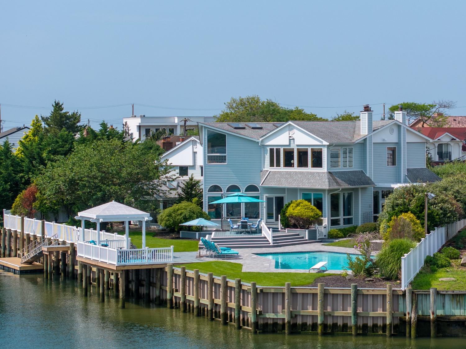 Nestled in a prime corner of Atlantic Beach Estates, this refined waterfront residence blends sleek coastal design with effortless indoor-outdoor living. Expansive walls of glass showcase sweeping bay views from the moment you enter, setting a striking tone throughout the home.

The main level offers a seamless flow ideal for both entertaining and everyday living. A custom kitchen with designer cabinetry and premium appliances opens to a banquet-sized dining area and multiple lounge spaces, all designed to capture the natural light and water views.

With six spacious bedrooms and six full bathrooms, the home provides flexibility for guests, work-from-home setups, or extended family. The private primary suite is a true retreat, featuring resort-style finishes and panoramic bay vistas from every angle. Additional bonus rooms across the home offer added versatility.

Outside, enjoy a heated in-ground pool, a newly updated bulkhead, and a private floating dock—perfect for boating, jet skiing, or simply relaxing by the water.

Located just moments from the beaches, shops, dining, and energy of the Barrier Island, with easy access to the Five Towns, JFK Airport, NYC, and the LIRR