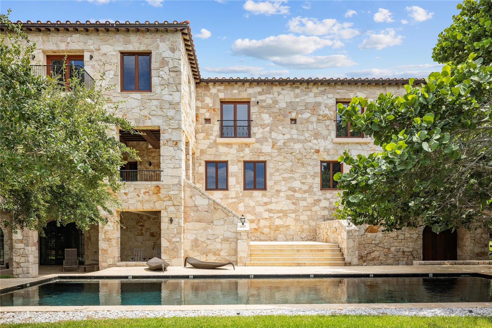 Welcome to "Tre Sorelle," a home of splendor and architectural authenticity, a true Tuscan farmhouse nestled in the premier waterfront community of Tierra Verde. From the early stages of its conception, which involved trips to Tuscany to research design and source materials, to the meticulous level of construction, every detail was given exceptional attention. This magnificent masterpiece provides seclusion and privacy, breathtaking beauty and luxurious quality that leaves a lasting impression. From the massive spread footings, concrete block structure (8" x 8" x 16" blocks) from foundation to roof line, and the first-floor living area situated at 13 feet above sea level, this home was constructed to withstand the tests of Mother Nature. In addition to the concrete block outer shell of the home, the entire exterior wall features a 10-to-12-inch layer of limestone quarried in the Province of Barletta-Andria-Trani and container shipped from Italy. The exterior walls are 18-to-20 inches thick in total, which is extraordinary, but perfect for Florida weather and lifestyle. The roof is a Ludowici Italian authentic cap and pan terra cotta roof tile with a 75-year warranty and the hurricane-impact windows and doors are a combination of Tischler und Sohn (U.S.A.) and Hope's Windows, the world's pre-eminent manufacturers of custom windows and doors. Encompassing over 12,000 square feet of luxury living, the home has seven bedrooms, eight full baths, three half baths, library, two offices, elevator, gym, and four-plus-car garage. Features of this home include soaring ceilings, impressive Douglas fir beam and plank work, solid mahogany doors throughout, and, extending from the lower-level entrance to the top floor, a beautiful cool honey-colored, pink veined Corton limestone spiral staircase, a stone steeped in French history emanating from the Burgundy region. The main level comprises an open floor plan with living room and gourmet kitchen, casual dining, formal dining room, two offices and a guest suite. The upper level features six en-suite bedrooms and a sun-filled library. The lower level has additional storage rooms, and gym. A tranquil oasis awaits outside, complete with expansive, covered lounging and dining areas, a fire pit surrounded by a moat and a salt-generating chlorine pool heated by a geothermal system, utilizing energy efficiency. Ideally located close to the thriving downtown of St. Petersburg and the Gulf beaches, less than 30 minutes to Tampa International Airport and yet perfect for those who are seeking peace and serenity.