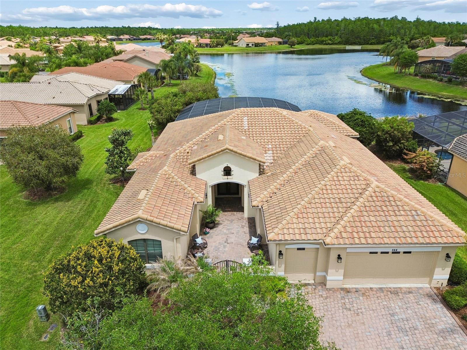 Rare Riviera model located in the highly sought-after Portofino Estates, showcasing breathtaking WATER VIEWS and a true oasis-style lanai complete with a gorgeous GUNITE POOL. Step through a welcoming GATED COURTYARD and elegant LEADED GLASS DOUBLE DOORS into a home where jaw-dropping views greet you from nearly EVERY angle. A CLIMATE-CONTROLLED SUNROOM adds approximately 400 square feet of ADDITIONAL LIVING SPACE, featuring HURRICANE-RATED, DUAL-PANE SLIDING GLASS DOORS and a MINI SPLIT SYSTEM INSTALLED in 2021, allowing for efficient, year-round comfort and true indoor-outdoor living. The dining room impresses with DOUBLE TRAY CEILINGS and PLANTATION SHUTTERS, creating an elegant space for entertaining. The chef’s kitchen is a true showstopper, highlighted by a FRAMELESS PICTURE WINDOW framing serene water views. It features GRANITE COUNTERTOPS, TRAVERTINE STONE BACKSPLASH, a large island with STORAGE on both sides, STAINLESS STEEL APPLIANCES, 42-inch cabinetry WITH PULL-OUT SHELVES and a custom-shelved closet pantry. The adjoining breakfast nook with a BAY WINDOW BUMP-OUT offers seamless sight lines to the water and flows effortlessly into the sunroom and lanai. PRIMARY SUITE includes TRAY CEILING with crown molding, direct access to the sunroom, and TWO SPACIOUS WALK-IN CLOSETS with custom built-ins. ENSUITE BATH features a TILED WALK-IN SHOWER with decorative listello border, DUAL VANITIES with separate sink areas, and a dedicated vanity/makeup space. SPLIT BEDROOM floor plan provides privacy, with two additional bedrooms, EACH offering its own ENSUITE BATH with walk-in showers and GLASS BARN-STYLE DOORS. The front flex room, complete with a closet, offers versatility as an office, den, or optional fourth bedroom and features custom built-in cabinetry and is enhanced by plantation shutters. EXTENDED and SCREENED lanai showcases panoramic water views, a private pool oasis, and added privacy, with EXTERIOR LIGHTING creating an ideal setting for evening enjoyment  or relaxation. Additional highlights include a LARGE laundry room with a STAINLESS STEEL SINK, WASHER AND DRYER INCLUDED, custom shelving in all closets, HVAC INSTALLED IN 2021 and a conveniently located HALF BATH. The garage features a 4-FOOT EXTENSION, ample storage, and a dedicated GOLF CART GARAGE. This exceptional home truly has it all—enjoy resort-style living right in your own backyard. Schedule your private showing today! The HOA: - maintains the LANDSCAPING & IRRIGATION systems in the common areas as well as at individual homesites - maintains the roads throughout the community - PROVIDES SECURITY with gate guards and mobile patrols including the Polk County Sheriff - allows AUTOMATED GATE ACCESS for residents via license plate readers - provides residents with Fiber Optic Internet & TV service.***Poinciana Lakes Plaza is a MAJOR NEW SHOPPING CENTER directly across from the Solivita Main Gate. It features Sprouts Grocery, TJ MAXX, Ross, Burlington, Rack Room Shoes, 5 Below, Ulta, Outback, First Watch, 5 Guys, Panda Express, Bojangles, Jersey Mike's Subs, 5 Guys, Papa John's Pizza, Burrito Bar, Cold Stone Creamery, Urgent Care, Dentist, Hand & Stone Massage, America's Best Eyeglasses, Crunch Fitness, Hair Cuttery, Petco, TD Bank, Verizon Mobile, PLUS MORE TO COME.***