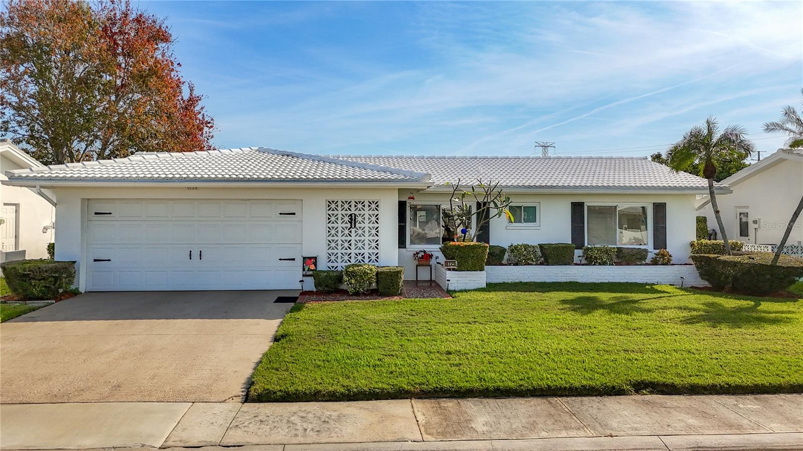 This beautifully remodeled Drayton model offers 2 bedrooms, 2 full bathrooms, and an oversized 2-car garage outfitted with multiple large storage cabinets for added convenience. The spacious galley kitchen showcases warm amber oak cabinetry with pullout drawers, solid-surface Corian countertops, a ceramic tile backsplash, newer stainless steel appliances, tile flooring, recessed lighting, and upgraded plumbing, creating a stylish and highly functional heart of the home. A designated office area sits just off the formal living room, providing a comfortable space for work or hobbies. The inviting open floor plan enhances the sense of space, with a cozy eating area in the kitchen and a bright, expansive family room at the rear that offers flexible dining possibilities and opens onto a large covered and enclosed lanai, ideal for relaxing or entertaining. Each bedroom features a walk-in closet, complemented by a deep hall closet and separate linen closet to ensure plentiful storage. The primary bedroom includes an en-suite bathroom with a shower, and both full bathrooms have been tastefully updated with granite-topped vanities and refreshed fixtures for a modern, polished look. Major systems and finishes have been thoughtfully maintained and improved, including a roof replaced in 2021, an air conditioning system replaced in December 2024, fresh exterior paint applied approximately two years ago, newer water heater, ceiling fans throughout, and beautiful, well-maintained walnut wood/laminate flooring. This home truly must be seen to be fully appreciated, as the list of upgrades and enhancements is extensive. Adding to its appeal is its location in the vibrant Mainlands Unit 4 community, which offers a clubhouse, shuffleboard courts, community pools, organized events, activities, and recreational facilities that support an active and social lifestyle.