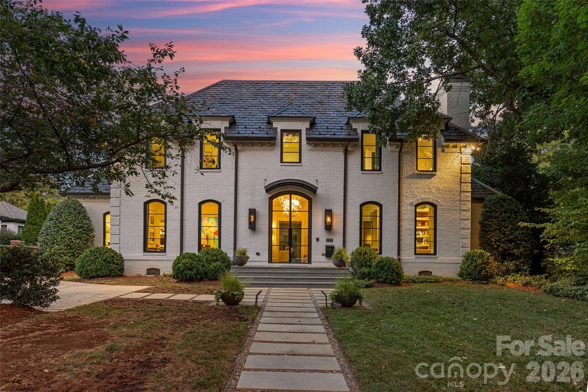 A rare blend of modern comfort and classic Georgian presence, this Eastover home balances impressive scale, livable elegance, and exceptional indoor-outdoor living in one of Charlotte's most desirable locations. Eleven-foot ceilings and five sets of steel-and-glass doors fill the interiors with natural light while creating a seamless connection to the outdoors.Main-level living is elegantly effortless: a generous dining room with a modern glass chandelier, a coffered-ceiling living room with a bar cleverly hidden behind custom steel and glass doors- beautifully appointed, and a private study with custom backlit shelving—each room anchored by its own fireplace.The open kitchen, morning room, and dining area form the spacious yet private hub of the home, with a built-in desk and custom cabinetry anchoring each space. The chef's kitchen features quartzite countertops, a Thermador professional gas range, Sub-Zero refrigerator and beverage refrigerator, and an oversized island with seating for eight. A separate scullery adds an additional beverage refrigerator, abundant cabinetry, and serving space.The main-level primary suite is a private retreat overlooking the rear yard and gardens, with dual custom closets, built-in cabinetry, and a custom bed; the spa bathroom has been recently refreshed. Upstairs, four ensuite bedrooms are complemented by an additional office or fifth bedroom and a central living room — flexible space for work, relaxation, or gathering. The third floor offers a full gym and sauna, plumbed for a future cold plunge. Control4 whole-home automation, museum-quality lighting, and automatic blinds round out the technology.The steel-and-glass doors open to a private bluestone terrace, pool, spa, and pergola. The terrace offers multiple entertaining areas, including seating around a wood-burning fireplace and a dining area. Beyond, the pool and spa are anchored by an open cabana with a gas firepit, all within a fully fenced yard offering room to play and mature, low-maintenance landscaping.  Rounding it out, the detached three-car garage adds versatility, with  conditioned wine storage and fixed stairs to future detached guest suite or even conditioned storage.727 Colville is a rare offering on one of Eastover's most sought-after streets.