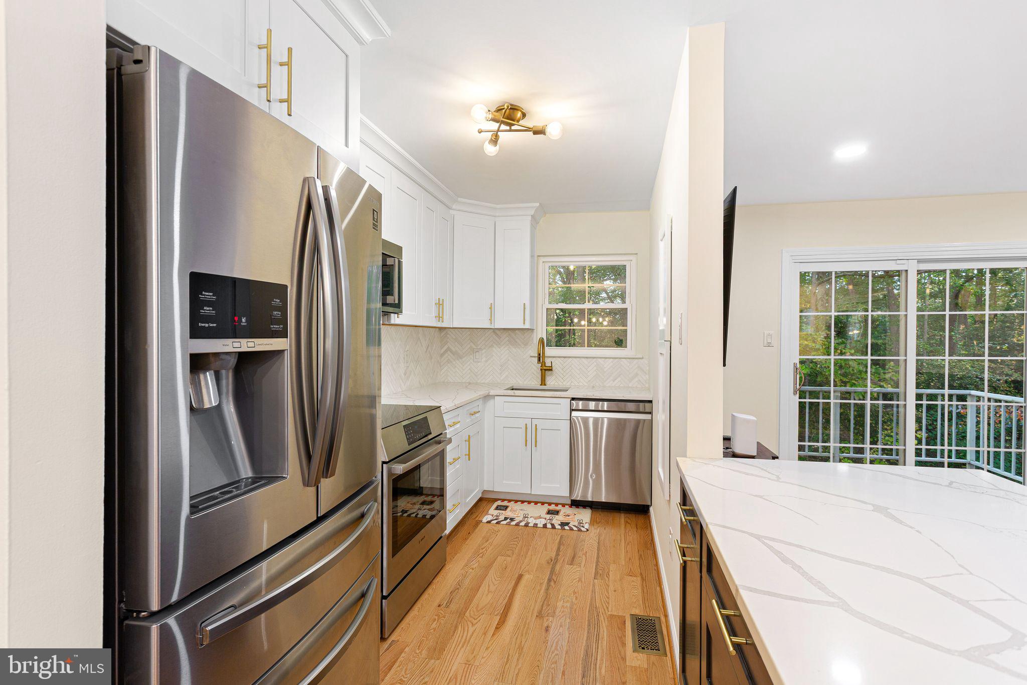 Smart design meets striking style in this gorgeous, fully upgraded 3-story home. Featuring 3 to 4 bedrooms and 3 bathrooms, this turnkey gem perfectly balances everyday luxury with effortless entertaining. The heart of the home is an open-concept living and dining space anchored by a sleek, modern kitchen. Outfitted with quartz countertops, soft-close cabinetry, a large breakfast peninsula, and premium new Bosch range and microwave, it flows seamlessly into a sun-drenched living area. Beyond the sliding glass doors, a large private deck overlooks a peaceful, wooded side yard—the perfect backdrop for evening cocktails. The upper level serves as a quiet retreat with three spacious bedrooms and two spa-inspired full baths. The primary suite boasts a dedicated en-suite bath and an impressive walk-in closet with a brand-new shelving system. The versatile lower level offers  walk-out sliders,  new Pergo flooring and an elegant electric fireplace. Serving as a potential 4th bedroom, media room, or home office, this level includes a convenient half bath, a  closet with ample storage, and a dedicated laundry room with brand new LG washer/dryer. Premium upgrades include: Smart & Secure: Smart locks on the front door and garage, plus a comprehensive new security system, smart camera doorbell linked to alarm system and front and rear exterior cameras. Modern Finishes: New hardwood flooring in the kitchen and upstairs hallway, brand new carpeting in upstairs bedrooms, updated railings in living space, and modern recessed lighting fixtures.  Attached Garage: 1-car garage featuring finished drywall, new door motor, and clean epoxy flooring, MyQ Smart Garage with built-in camera.