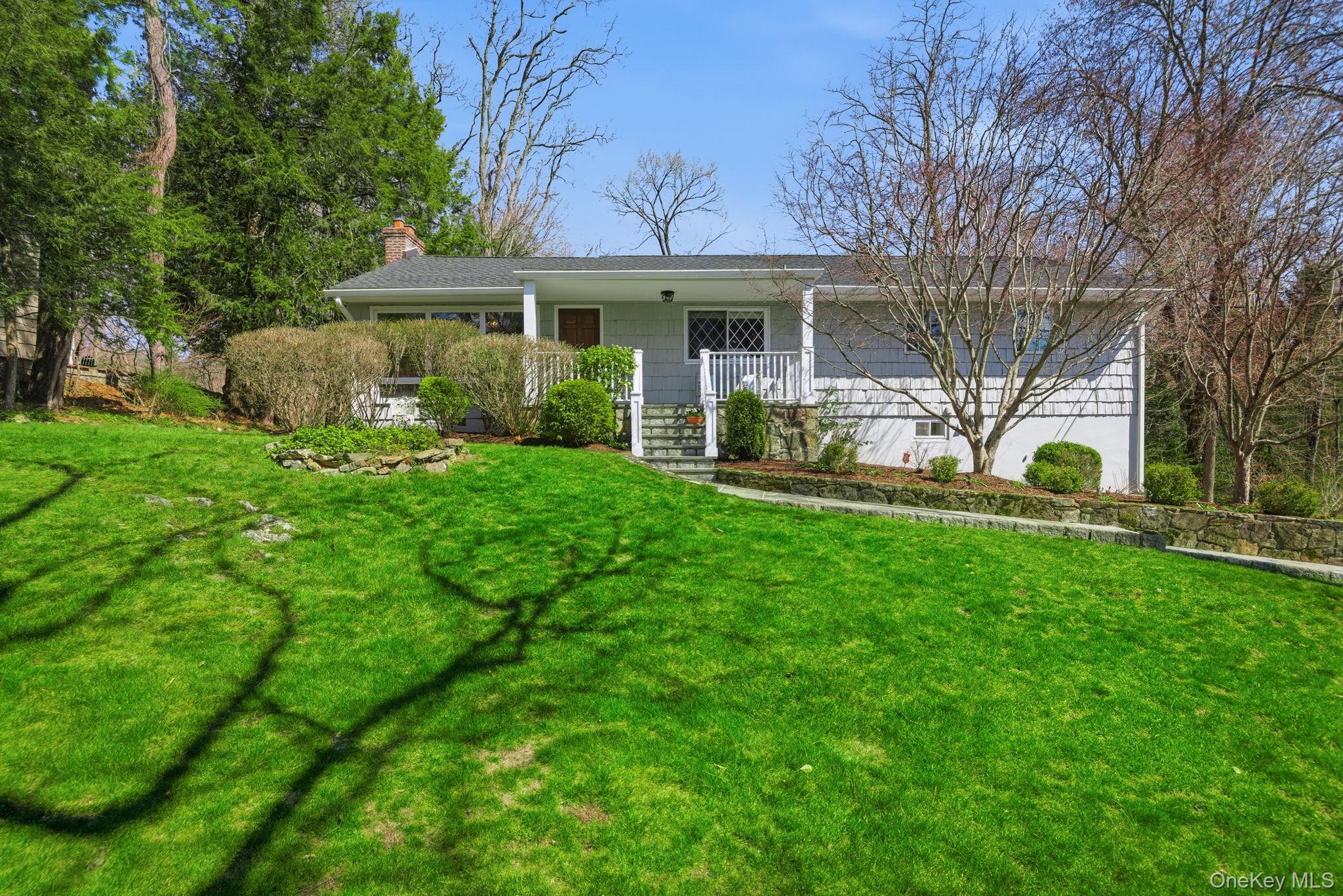 Welcome to 26 Meadow Lane, a pristine 2,178-square-foot ranch set on over half an acre of flat, beautifully landscaped property in one of Chappaqua’s most coveted residential neighborhoods. A rocking chair front porch and Belgian block-lined driveway offer an immediate sense of arrival, while sidewalk-lined streets connect the neighborhood to the acclaimed village of Chappaqua, minutes from restaurants, shopping, playgrounds, the library, Metro-North rail service, and more. Situated within the highly sought-after Chappaqua Central School District, including Roaring Brook Elementary and Robert E. Bell Middle School. The sun-drenched main level features a cathedral-ceiling living room anchored by a dramatic stone fireplace that adds immediate texture, warmth, and luxury to the space. The formal dining room overlooks a stunning yard, while the expansive skylit eat-in kitchen with cathedral ceiling offers an abundance of counter space, a center island, and a built-in entertaining hutch with glass-front cabinetry. A screened porch flows to an expanded stone patio below that lives like a true outdoor living room, seamlessly extending your entertaining space into the beautifully level yard. The primary suite with renovated en-suite bath, two additional bedrooms, a full hall bathroom, and a home office complete the main level. The lower level is anchored by an expansive family room with slider to the patio, complemented by a mudroom, laundry room, half bath, and generous storage throughout. Additional highlights include wood floors, custom closet organizers, extensive crown molding throughout, whole-house generator hookup, dual-zone heating and central air, two-car attached garage, and fresh paint throughout. Legal three-bedroom with flexible four-bedroom living, 2.5 baths, septic, public water, and natural gas. Immaculate, versatile, and perfectly positioned for future expansion.