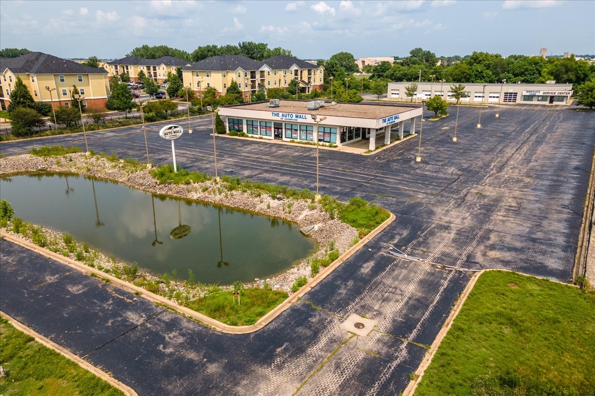 Command attention in the heart of Champaign's bustling business corridor with this turnkey, highvisibility commercial opportunity-purposebuilt for automotive sales and service, and primed for your next successful venture.    Positioned among major-brand dealerships and just blocks from Market Place Mall, this morethan4acre property boasts over 300 feet of street frontage, an expansive asphalt lot for 400+ vehicles, and a private lake that adds a distinctive sense of polish and presence the moment you arrive. The setting feels both energetic and elevated: steady traffic, easy highway access, and a striking, professional streetscape.    The front showroom building (approx. 6,200 sq ft) welcomes clients with an airy, lightfilled reception area framed by high ceilings and wide stretches of glass. Natural light pours across gleaming floors and open display space, creating an inviting backdrop for vehicles, retail inventory, or professional offices. Multiple private manager's offices and numerous staff workstations support smooth daytoday operations, while a dedicated break room and customer refreshment center keep employees and guests comfortable. Separate men's and women's restrooms add convenience and capacity for higher customer volume.    The second, freestanding building (approx. 9,000 sq ft) is a fully functional auto service facility, currently leased and generating $10,000/month NNN. It features a 9bay repair shop with generous workspace, an office area for service writers or administration, and an auto parts retail room that can be merchandised to your needs. This immediate income stream provides a builtin return while you operate from or repurpose the front building.    Every aspect of the site has been designed for business efficiency and customer ease: wide drives, generous maneuvering room, and expansive, fully paved parking that is ideal for a large inventory display, fleet staging, or hightraffic customer parking. The private lake and long frontage enhance curb appeal and brand presence, creating a memorable first impression for clients and partners alike.    Offered for sale with the option to lease the front showroom/office building at $12,000/month NNN, this property delivers rare flexibility. Continue its legacy as a thriving auto dealership, expand service operations, or reimagine it for another highimpact use-powersports, RVs, equipment sales, medical or professional campus, retail showroom, or corporate headquarters. The infrastructure is in place; the possibilities are limited only by your vision.    Move into a modern, updated, keyinready facility in one of Champaign's most coveted commercial zones. Schedule your private tour today and position your business at a location your customers-and competitors-won't be able to miss.