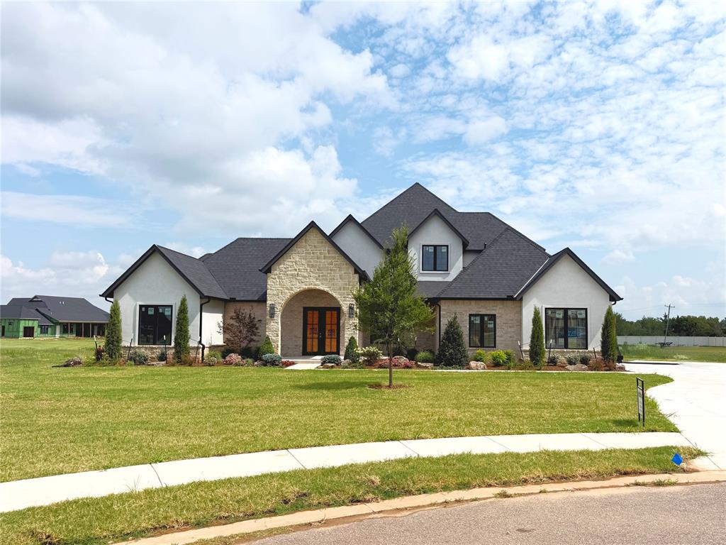 LUXURY POND VIEWS | ONE ACRE | GATED COMMUNITY | DEER CREEK SCHOOLS – Tucked away on a quiet cul-de-sac in an exclusive gated Edmond community, this exceptional new home sits on a private one-acre homesite backing to a neighborhood pond with a fountain, creating peaceful views and a picturesque setting. Thoughtfully designed with every bedroom downstairs, the floor plan includes a private guest suite with its own full bath, while upstairs offers a spacious bonus room with a half bath. A striking stone arch entry and impressive 8-foot wrought iron and glass double doors welcome you inside, where white oak hardwood floors and upscale architectural details set the tone. The vaulted living room showcases a dramatic floor-to-ceiling stone fireplace with gas logs, flanked by custom built-in bookcases. Designed for entertaining, the chef's kitchen centers around a massive 3' x 7.5' island with breakfast bar seating and abundant storage. Premium features include double ovens, a 5-burner gas cooktop with pot filler, commercial-style French door refrigerator/freezer, ceiling-height cabinetry, geometric tile backsplash, walk-in pantry, butler's pantry, and built-in hutch. The sun-filled dining area is wrapped in windows overlooking the backyard. Outdoor living is equally impressive with nearly 700 square feet of covered patio space, including a private patio off the primary suite and an expansive covered patio featuring a built-in stone fireplace overlooking the pond and fountain. Additional highlights include 8-foot garage doors, Wi-Fi garage door openers, a smart home system with Wi-Fi, Bluetooth and Z-Wave integration, full sprinkler system, and hybrid insulation with spray foam exterior walls and blown-in attic insulation for exceptional energy efficiency, comfort, and a remarkably quiet interior. Luxury finishes, an outstanding floor plan, and one of the community's premier homesites make this an exceptional opportunity in highly sought-after Deer Creek Schools. Come See!