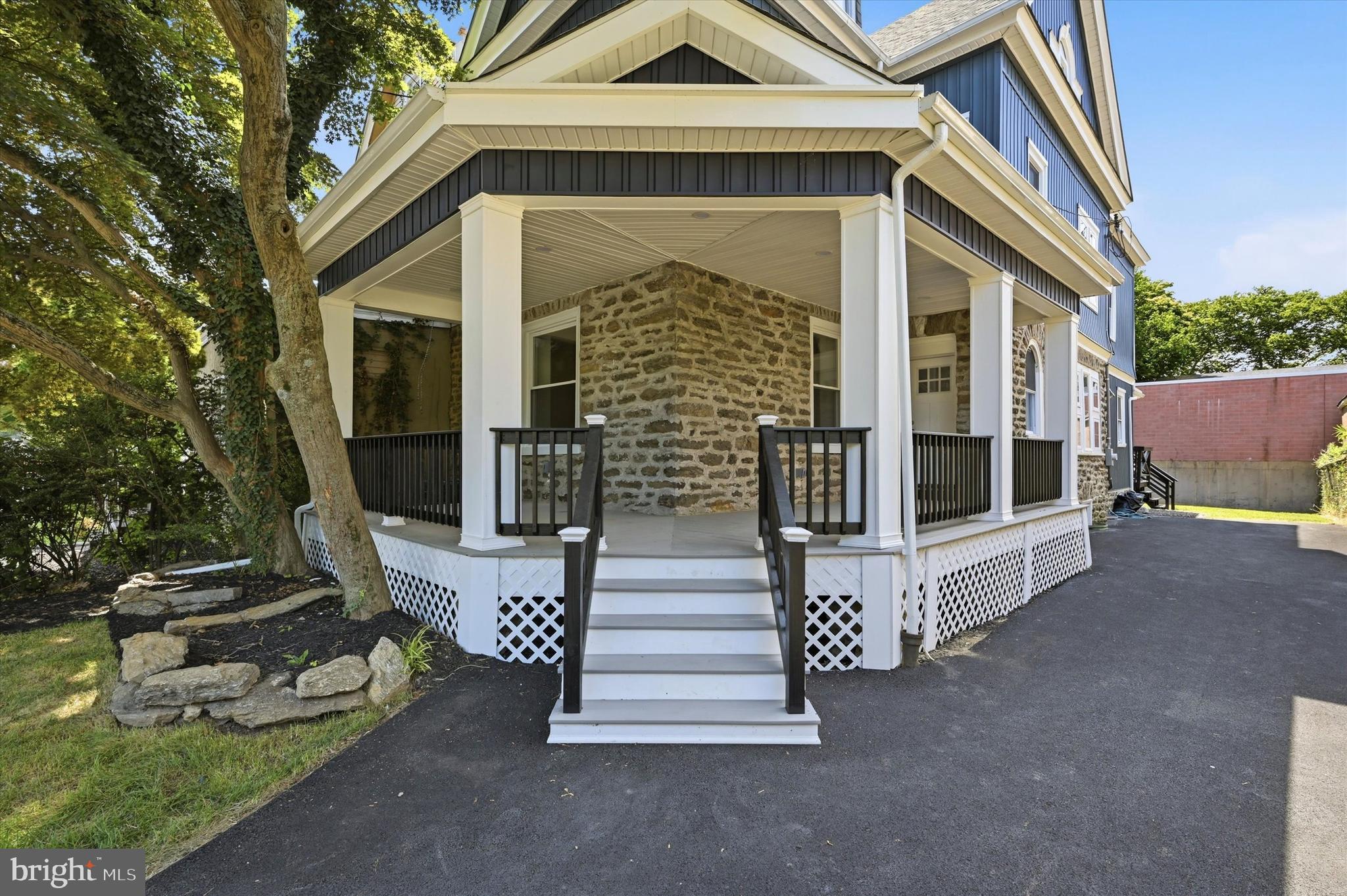Discover this meticulously renovated three-story twin offering modern luxury, timeless charm, and the added benefit of a pending 10-year tax abatement. From the moment you arrive, you'll appreciate the expansive five-car driveway, beautifully landscaped front yard, and inviting wraparound porch accented by original stone details and a classic blue exterior. The setting feels like a peaceful retreat while remaining conveniently close to everything the city has to offer. Inside, the home is filled with natural light thanks to oversized windows, luxury white oak-look vinyl flooring, and crisp white finishes throughout. The first floor features a welcoming formal sitting room, a stylish centrally located powder room, and an impressive open-concept living space designed for both everyday living and entertaining. The chef's kitchen is the heart of the home, showcasing granite countertops, Tafisa cabinetry, a large center island with built-in microwave and additional storage, a stainless steel appliance package, and a custom built-in wall unit ideal for hosting gatherings. The adjoining living and dining areas offer endless possibilities for furniture layout and design. Just off the kitchen, a covered rear porch overlooks the spacious backyard, creating the perfect setting for morning coffee, outdoor dining, or relaxing evenings. The fully finished lower level provides exceptional flexibility with two separate rooms and a beautifully appointed full bathroom featuring a large walk-in shower. Whether used as a guest suite, home office, gym, media room, or additional living space, this level adapts to your needs. Upstairs, the second floor features a spacious primary suite complete with a double-sided walk-in closet and a luxurious en-suite bath with a double vanity and oversized walk-in rain shower. An additional bedroom and a beautifully finished hall bathroom offer comfortable accommodations for family or guests. A conveniently located laundry alcove with built-in shelving, along with a brand-new washer and dryer, adds everyday convenience. The third floor offers two more generously sized bedrooms with charming architectural details, as well as a fourth full bathroom with a stylish walk-in shower. Ideally situated between Oak Lane and Melrose Park, this home is just minutes from the shopping, dining, and everyday conveniences along Cheltenham Avenue. With easy access to Broad Street, commuting is simple, and major destinations including Einstein Medical Center, Temple University Health System, and Center City Philadelphia are all within a short drive. This exceptional home combines thoughtful design, generous living space, and a prime location. Schedule your private showing today or visit one of our upcoming open houses—you won't want to miss the opportunity to experience this beautiful home in person.