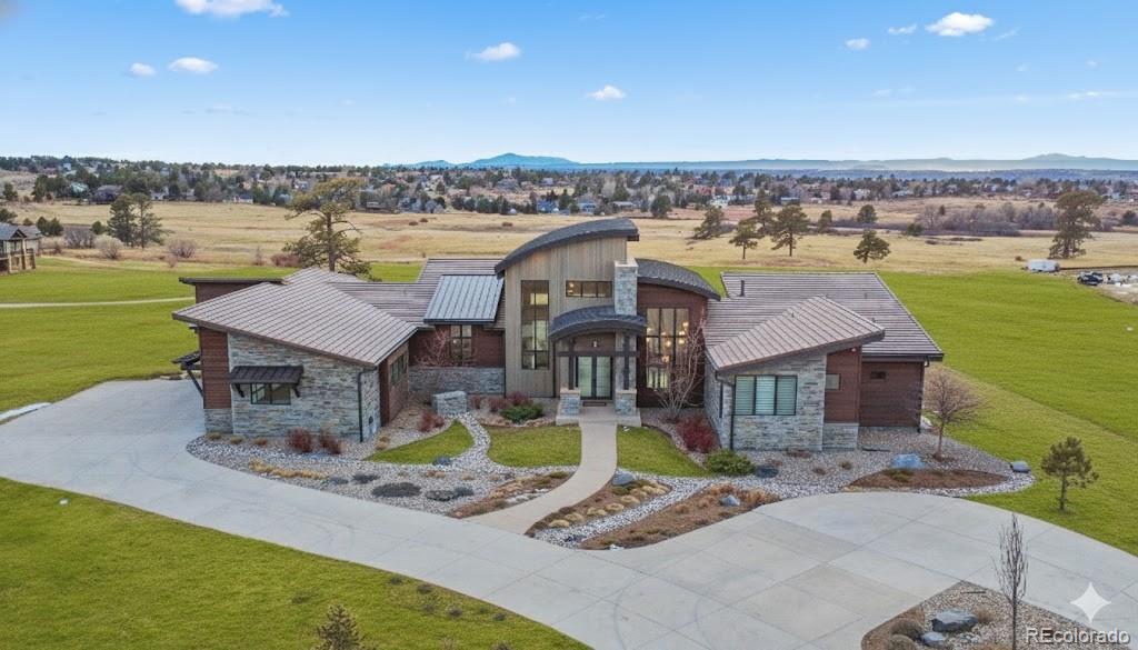Tucked behind the gates of one of Colorado’s most coveted communities, this Sterling custom residence is a masterful expression of luxury, tranquility, and timeless design. Bathed in natural light, the home presents a clean, contemporary aesthetic thoughtfully balanced with warmth and intention. Walls of glass and dramatic bifold doors blur the boundary between indoors and out, opening to multiple private balconies that frame sweeping views of Pikes Peak, the Front Range, and open space.Situated within the gated and guarded, invite-only Colorado Golf Club community, this exceptional home offers a rare level of privacy and serenity-where abundant wildlife and natural beauty define the landscape—all just moments from the conveniences of Parker city limits. Here, quiet mornings, golden sunsets, and expansive horizons are part of everyday life.Custom features are seamlessly integrated throughout, including a four-car attached garage, a custom circular drive ideal for guests or car enthusiasts, an entryway mudroom, walk-in pantry, private office, and multiple bedrooms with ensuite bathrooms and generous walk-in closets. Designed for both refined daily living and elevated entertaining, the home offers a designated coffee bar, a dedicated entertainer’s bar and lounge in the lower level, laundry rooms on each floor, and a glass-enclosed wine room with an inviting seating area. Additional highlights include multiple private balconies, an outdoor grilling terrace off the kitchen, three inviting fireplaces, Gaggenau luxury appliances, soaring ceilings, and more than two acres of maintained land, complete with an invisible pet fence. This is a home meant to be experienced, where thoughtful architecture, inspired design, and breathtaking surroundings reveal themselves at every turn. Opportunities within the Colorado Golf Club are rare, and homes of this caliber are even rarer—an exceptional property for those who have been patiently waiting for something truly extraordinary.