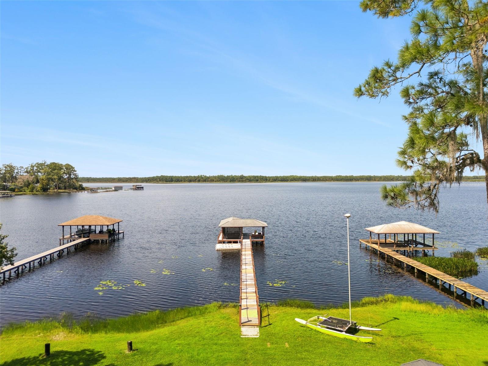 Under contract-accepting backup offers. ~ LAKEFRONT LIVING ~ on Lake Mary Jane doesn’t get much better than this! Beautifully upgraded and designed to make the most of its incredible WEST-FACING WATER VIEWS, this Isle of Pines home delivers privacy on 1.75 ACRES, sunsets and an outdoor living space that feels like a true retreat. Major updates include NEW WINDOWS (2025), REMODELED KITCHEN and NEW FLOORING (2024), ROOF (2023), UPDATED A/C (2021), refreshed LAUNDRY ROOM (2020) and WATER HEATER (2019). The septic was also serviced approximately 2.5 years ago. Inside, most of the living is conveniently located on the main floor, including your PRIMARY SUITE and two additional bedrooms. The beautifully updated kitchen was created with the home chef and entertainer in mind, featuring high-end finishes and appliances, complemented by a stylish wine/coffee in the dining area. Upstairs, a light-filled LOFT that opens to a private balcony adds flexible space for an additional living area, office, hobby room or whatever fits your lifestyle. The showstopper is out back ~ expansive LAKE MARY JANE VIEWS stretch toward Moss Park on the opposite shoreline, creating a backdrop of water, trees and spectacular SUNSETS. The lodge-inspired outdoor living area features TEAKWOOD DECKING, an extensive BUILT-IN SUMMER KITCHEN, WOOD-FIRED PIZZA OVEN and GAS FIREPLACE – an exceptional setup for entertaining or simply enjoying life on the lake. Follow the view through your fenced yard out to the PRIVATE DOCK with additional COVERED SEATING and a functional BOAT LIFT. Bring your boat and start enjoying the water directly from your own backyard! Adding even more versatility is a DETACHED GARAGE with a spacious AIR-CONDITIONED BONUS ROOM upstairs – ideal for recreation, a home office, gym, studio, potential guest space or garage apartment. Located in the established Isle of Pines community in the Lake Nona/Moss Park area, Lake Mary Jane is a SPRING-FED LAKE spanning more than 1,100 acres with CANAL ACCESS to nearby LAKE HART. The optional Isle of Pines Property Owners Association offers access to a community park and boat ramp along with neighborhood events throughout the year. Upgraded, distinctive and built around an incredible waterfront lifestyle, this is a rare opportunity to enjoy space, privacy and unforgettable sunsets directly on Lake Mary Jane. Call today to schedule a tour and fall in love with your new HOME SWEET ‘LAKE’ HOME! ***Seller may consider buyer concessions if made in an offer and additional items (jet ski's, trailer, floating docks, pontoon boat... available for separate purchase, calll for details!***