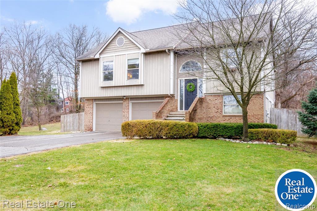 Welcome to this beautiful home just minutes from downtown Milford, offering the perfect blend of privacy, space, and convenience. Nestled on just under 2/3 acre with scenic wooded views, this spacious property provides a peaceful setting while remaining close to shopping, dining, and major expressways.This charming home features approximately 1,937 square feet of living space, with 3 bedrooms and 2 full bathrooms. The open and inviting main living area is flooded with natural light and offers plenty of room for relaxing or entertaining guests. The finished walkout lower level provides additional living space that can be used as a home office, playroom, or recreation area, along with a full bathroom. Step outside to enjoy the large backyard, complete with a deck off the great room—perfect for summer gatherings, outdoor dining, or simply enjoying the peaceful surroundings. Additional highlights include: Oversized 2 car attached garage with built-in storage. Large fenced in yard. Bonfire area in the wooded backdrop. Generous parking and setback from the road for added privacy. Conveniently located near Kensington Metroopark, bike/walk trails, GM Proving Grounds and with quick access to Interstate 96, this home offers an easy commute while still enjoying the charm of a small-town community. New septic tank and field summer 2025, most of interior professionally painted fall 2025, water heater 2024Open House 3/22/26 1-3pm