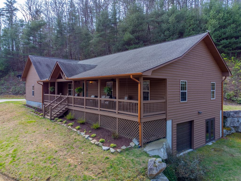 Hand-hewn log-sided home on 16.74 UNRESTRICTED acres w/ NO HOA or deed restrictions, PLUS an RV site w/ septic & power available! This well-maintained 3BR/2BA home offers privacy, functionality & mountain charm. The main level features an XL living area w/ a gas log fireplace, tongue-&-groove walls, & gleaming hickory hardwood floors throughout (except baths & laundry). The kitchen is equipped w/ granite countertops, ample cabinet & counter space, & a cozy breakfast area. The primary suite includes an ensuite bath w/ dual vanities, while two additional bedrooms & a full bath complete the main level. A dedicated home office w/ Starlink internet makes working remotely a breeze. Enjoy outdoor living w/ a covered front porch overlooking your acreage & a private rear porch. The property also includes a 2-car attached garage plus a 1-car garage in the unfinished basement, which is already plumbed for a half bath—offering expansion potential. With nearly 17 acres of unrestricted land, there's room to hike, hunt, explore, or even build an additional home(s) Conveniently located less than 10 minutes from downtown Robbinsville, this property offers both seclusion & convenient access