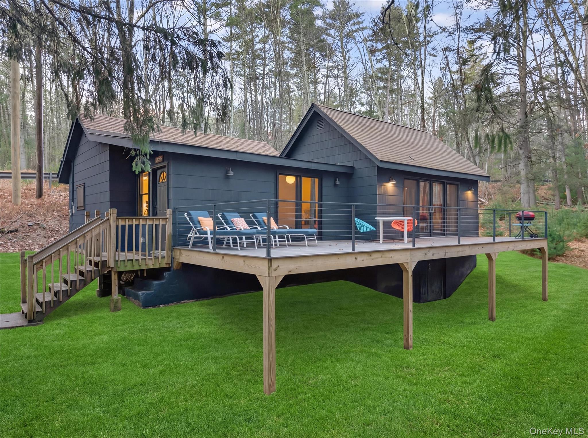 Back of property with a lawn, a wooden deck, and roof with shingles