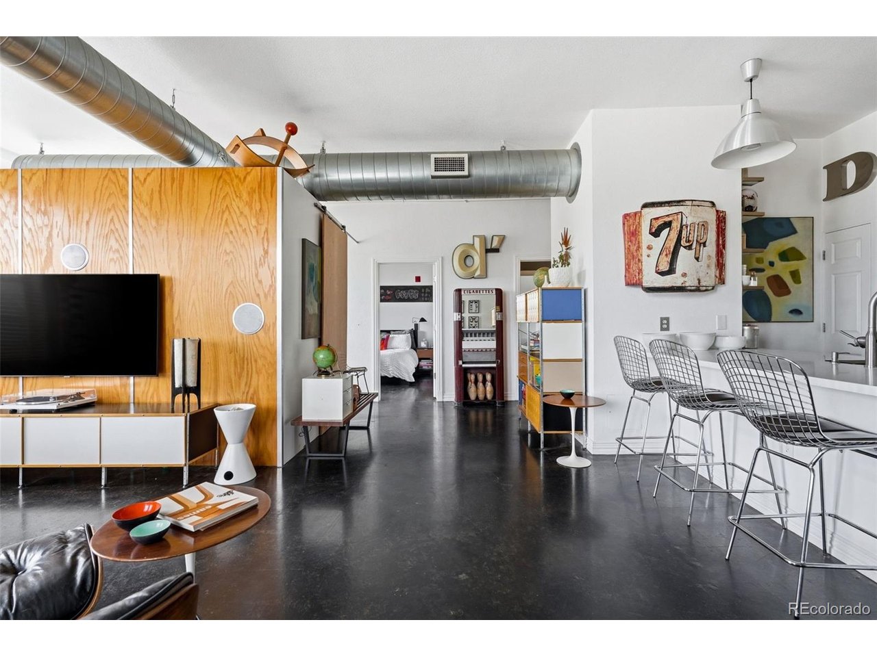 Urban loft style meets effortless city living at Baker Commons. Set in the heart of one of Denver's most vibrant corridors, this stylish 2-bedroom, 1-bath condo offers 1,113 square feet of flexible living space with the industrial character buyers love-exposed ductwork, polished concrete floors, tall ceilings, and oversized windows that flood the home with natural light.The open-concept layout is designed for both everyday living and entertaining. The kitchen features stainless steel appliances, warm wood cabinetry, a subway tile backsplash, and a large peninsula with seating for four, flowing seamlessly into the spacious living and dining areas. Built-in surround sound speakers create an immersive experience for movie nights and music, while a thoughtfully designed desk nook provides the perfect work-from-home setup.The primary bedroom offers generous closet space and direct access to a private covered balcony, an ideal retreat for morning coffee or unwinding at the end of the day. The second bedroom provides flexibility for guests, a home office, fitness space, or creative studio. A full bathroom and in-unit laundry add convenience and functionality.Rare for such a walkable urban location, this home includes two dedicated parking spaces along with a private storage locker in the garage, providing ample room for bikes, seasonal decor, and outdoor gear.Located at 277 Broadway in the sought-after Baker neighborhood, this condo places Denver's best restaurants, coffee shops, boutiques, bars, and music venues just outside your door. With quick access to downtown, the Cherry Creek Trail, South Broadway, and major commuter routes, this is a true lock-and-leave lifestyle for buyers seeking style, convenience, and an unbeatable central location.