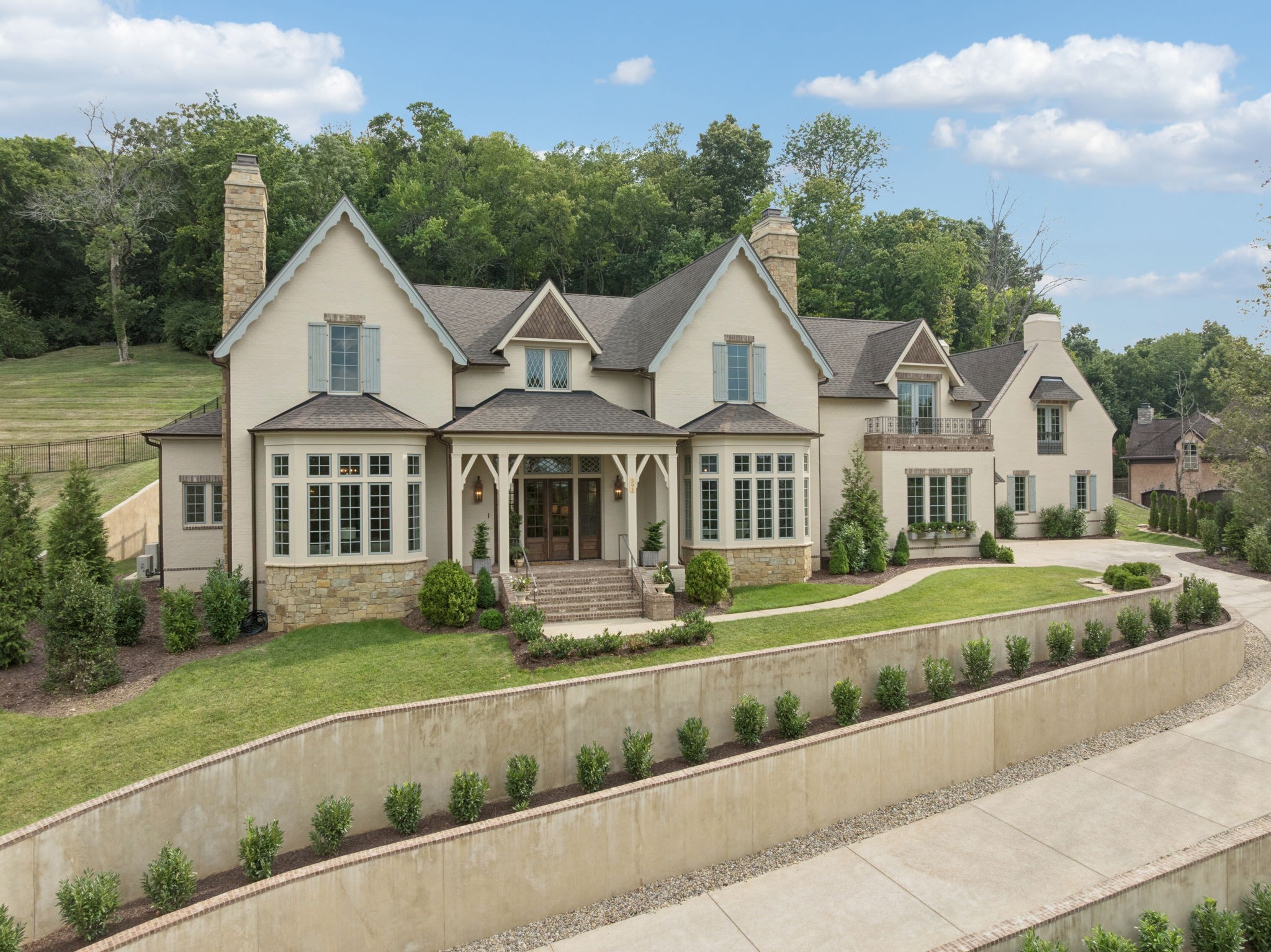 Nestled in the scenic hills of Avalon, this European Countryside-inspired estate is a masterpiece of design and craftsmanship. With the recently finished flex space… this thoughtfully envisioned residence  by Garden Gate Homes, seamlessly blends timeless elegance and charm with modern comfort, creating an atmosphere of sophistication and warmth. Step inside to find an expansive, light-filled interior where handcrafted millwork, custom cabinetry, and oversized windows create a warm and refined atmosphere. The breathtaking vaulted kitchen, with exposed beams and top-of-the-line appliances, is as stunning as it is functional, complete with a scullery and a charming coffee nook. The private office, bathed in natural light and featuring a fireplace, offers a peaceful workspace with beautiful views. The main-level primary suite is a true sanctuary, featuring a custom walk-in closet, double vanities, a dedicated makeup vanity, and a walk-in, floor-to-ceiling tiled shower with a soaking tub. Upstairs, three additional en suite bedrooms offer unparalleled privacy, each with their own unique charm. Two second-story balconies provide the perfect place to take in the picturesque surroundings. Designed for both luxury and functionality, this home offers two large finished flex spaces, presenting endless possibilities—a guest suite, playroom, theater, fitness room, or additional entertainment space. A four-car garage, breezeway, and laundry hookups on both levels add to the convenience of everyday living. Outside, the pea gravel courtyard, raised garden boxes, and lush landscape create a serene outdoor retreat, ideal for relaxing or entertaining. This rare opportunity offers the perfect balance of architectural richness and modern comfort, set on a private, picturesque lot in one of Middle Tennessee’s most sought-after communities. Schedule your private tour today!