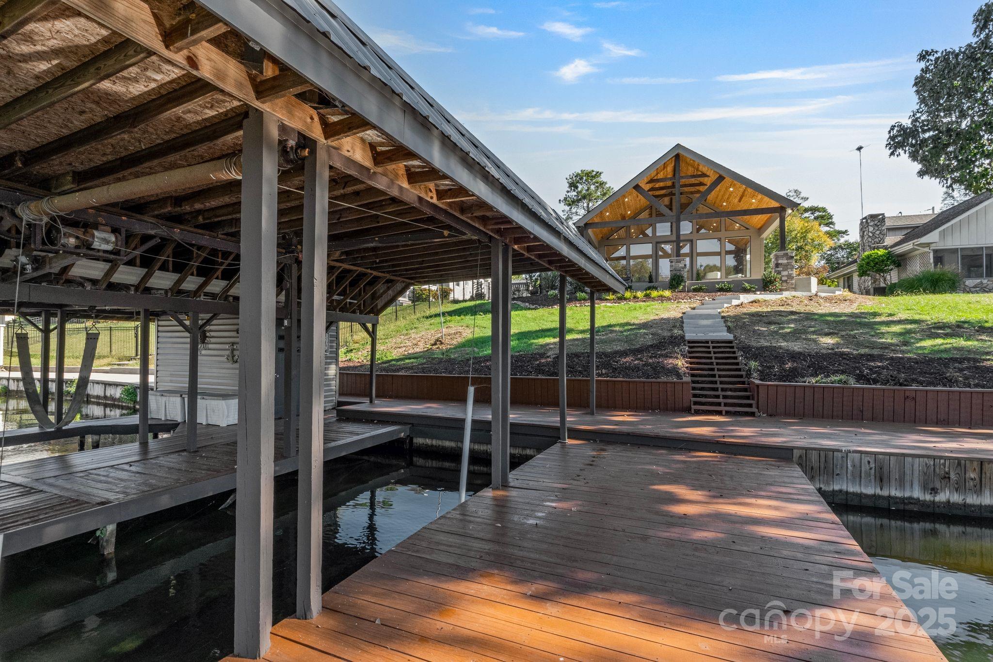 This beautifully remodeled and furnished Lake Tillery waterfront home offers 1,731 sq. ft. of open living space all on one level with soaring cathedral ceilings in both the great room and primary suite. It features 2 bedrooms, 2 full baths, and 2 versatile bonus rooms. Every detail has been updated — new roof, kitchen, bathrooms, flooring, windows, and concrete driveway. A wall of glass and sliding doors in the great room make it feel as though the lake is right at your door. The kitchen features natural cherry cabinets, granite countertops, new stainless appliances, and a built-in flat-black china cabinet. The large covered porch with tongue-and-groove pine ceiling mirrors the warmth of the great room. Enjoy peaceful cove views extending to the main channel and Garrison Bridge. With deep water and a spacious two-slip boathouse this home defines lake living at its best!