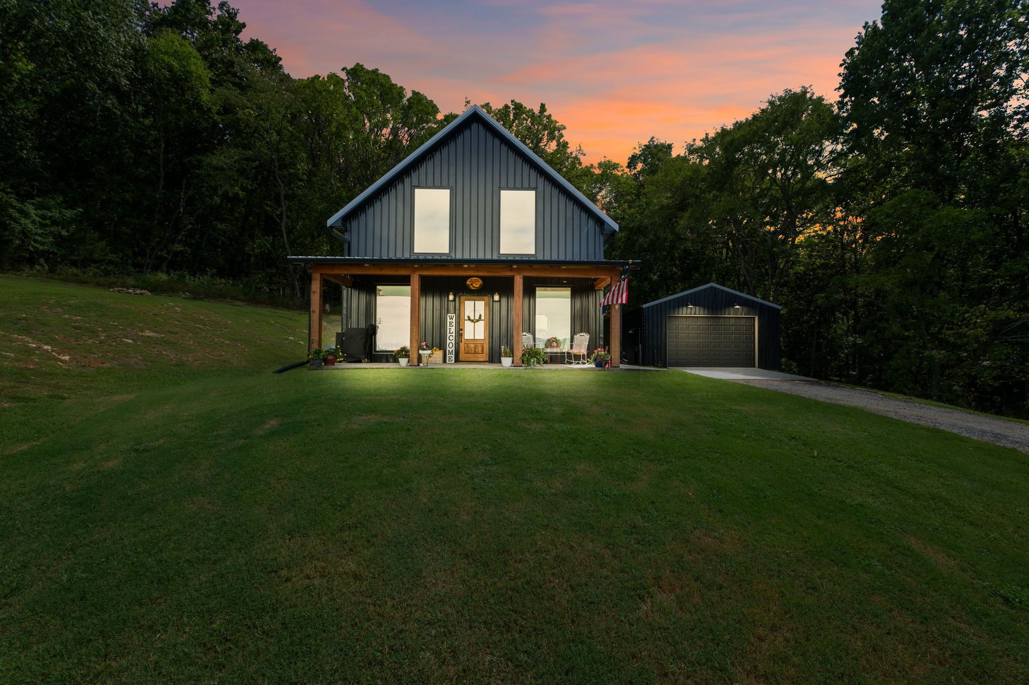 Barndominium Beauty! This newly built stunning home combines rustic charm with modern luxury, offering high-end finishes throughout. Step inside to soaring tongue and groove ceilings,  an open-concept floor plan, and designer touches at every turn. The gourmet kitchen features custom cabinetry, upgraded appliances, and a spacious island made of leathered Marble, perfect for entertaining and cooking. The microwave also air fries, the oven is convection and air fryer, the cooktop is induction, and the freezer boasts craft ice.  Relax in the serene primary suite with a spa-inspired bath, or enjoy gatherings in the expansive living area filled with natural light and amazing views from inside, or on the second floor balcony.  Durable construction meets elegant style, creating a one-of-a-kind property that’s both functional and breathtaking.  The serene land is nearly 14 acres of woods with a natural spring, deer and turkey. The detached 2 car garage offers finished space as well as room for all your toys or vehicles and a RV plug.  At the base of the parcel there is room to build a shop or park recreational vehicles.  Underground electric service means no wires to obstruct your view from the timber framed front porch.On demand propane powered water heater.  True country luxury living, and just 45 minutes to Nashville. Bring your rocking chairs for the best porch sitting you can imagine!