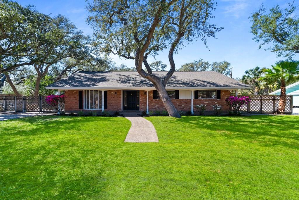 LITTLE BAY SHORES GEM! Welcome to this immaculate 3-bedroom, 2-bath brick beauty with a dedicated office, tucked into the highly desirable Little Bay Shores neighborhood. Sitting pretty on an oversized third-acre lot, the property is shaded by gorgeous mature oak trees that provide both charm and a little extra Texas sun protection. Inside, the flexible layout offers formal living and dining spaces that can easily pull double duty as a home office, playroom, hobby space, or whatever your lifestyle calls for. The cozy den, complete with a classic brick fireplace, opens to the kitchen and main living areas—perfect for everyday living, entertaining friends, or simply relaxing after a long day. Recent updates mean much of the work is already done for you: fresh interior paint, new landscaping, new carpet, new granite bathroom countertops, tile flooring in the kitchen and baths, and a resurfaced primary shower. The split-bedroom layout provides privacy for the primary suite, while thoughtful extras include a sprinkler system, partial hurricane shutters, a bonus utility/storage room, and a large rear-entry two-car garage with a fully fenced and gated driveway. Out back, the spacious yard and large concrete patio are ready for backyard barbecues, boat & RV parking, or finally hosting that gathering you've been talking about. And the cherry on top? You're just blocks from the bay, with easy access to water, local restaurants, shops, and everything that makes Rockport living so special!