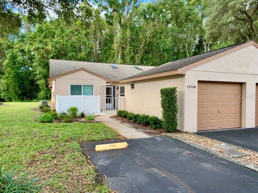 Completely remodeled and truly turn-key, this beautifully updated condo offers quality upgrades throughout. Features include new CWS triple-pane impact-resistant vinyl windows, premium maple kitchen cabinetry with plywood construction, granite countertops, and new Whirlpool deluxe stainless-steel appliances. Both bathrooms have been fully renovated, highlighted by a custom tiled walk-in shower with frameless glass doors in the primary suite. Life-Proof high-traffic luxury vinyl plank flooring and fresh paint complete the interior. The kitchen, living, and dining areas showcase vaulted ceilings, abundant natural light, and an open, spacious design. An adjacent bonus room provides flexible space for a den, office, or guest area. Large sliding doors from both the living room and primary bedroom open to a private lanai featuring four-season sliding windows that can be easily removed to enjoy cool, breezy days. Additional highlights include an adjacent one-stall garage and a large private front patio with brick pavers. Pine Ridge at Sugar Creek is a quiet, gated 55+ community surrounded by mature trees and natural scenery. Amenities include a large year-round heated pool and hot tub, pickleball court, clubhouse with planned activities, open green spaces, ponds, and natural habitats throughout. The association covers exterior maintenance, digital cable with high-speed internet, trash, water, and sewer. One pet under 25 lbs is permitted. Ideally located with a new Aldi just across the street, only 5 minutes to Publix and the Suncoast Parkway (SR-589), less than an hour to area airports, and just a 15-minute drive to the beautiful Gulf Coast.