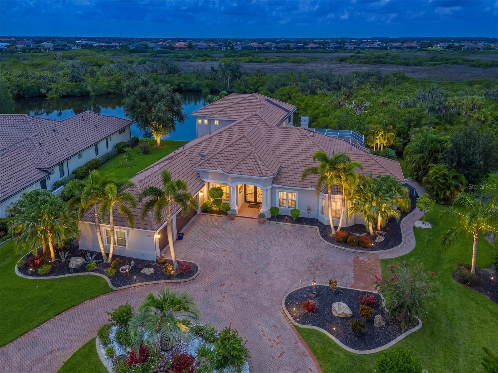 Welcome to this exceptional Rutenberg-built executive home, beautifully situated within the gated community of River Wilderness. From the moment you enter through the dramatic 10½-foot custom steel doors, you’ll appreciate the quality, thoughtful design, and exceptional attention to detail throughout.The spacious foyer immediately showcases stunning water views, which can be enjoyed from nearly every major living space. The formal living room features a signature aquarium window, while the breakfast nook, family room with disappearing corner pocket sliders, and luxurious primary suite all capture the serene waterfront setting.This impressive home offers five bedrooms and five-and-a-half baths, including three ensuite guest bedrooms that provide comfort and privacy for family and visitors. The formal dining room comfortably seats 10 and is ideal for elegant entertaining.The expansive primary suite is a true retreat, featuring a luxurious bath and an extraordinary walk-in closet. A separate office with custom built-in shelving provides the perfect space for work, reading, or displaying treasured collections.Upstairs, a spacious bonus room offers a wet bar and access to a large, freshly rescreened deck overlooking the beautiful pond. This level also includes an additional bedroom and full bath, creating a private retreat for guests or extended family.Three fireplaces add warmth and ambiance throughout the home—one in the formal living room, another in the great room, and a third in the outdoor lanai seating area.The current owners have made numerous significant improvements, including:- Updated bathrooms throughout- Impact windows and sliders on both levels- Bamboo plank stair treads leading to the bonus area- Power shades for the double sliders in the great room and the bonus-room window- Two of the three HVAC systems replaced approximately three years ago- New pool equipment control panel- Fresh interior and exterior paint, including the three-car garage- Backup generator serving the downstairs air conditioning and two refrigerators- Central vacuum system, which will be warranted to the new owner- Home warranty included with the saleLocated in the desirable gated community of River Wilderness, residents enjoy a beautiful natural setting and the option to participate in a voluntary golf membership, as well as social and tennis memberships.This extraordinary home combines luxury, privacy, indoor-outdoor living, and extensive recent updates in one of River Wilderness’s most desirable settings. A truly special opportunity to enjoy the Florida lifestyle at its finest.