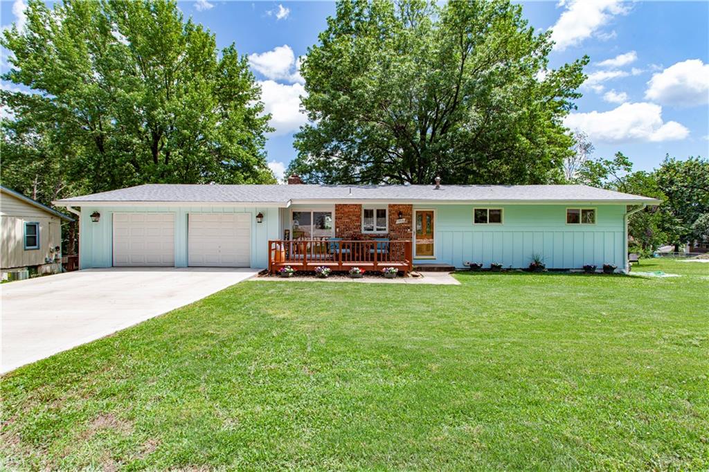 Welcome Home! Beautifully UPDATED Lake Tapawingo Ranch! Peaceful setting with view of lake from back balcony. Half Acre Lot is shaded by Flowering Dogwood, Redbud and Sweet Gum Trees. Fenced backyard and patio create a perfect setting for relaxing, entertaining and privacy. The Newly Refinished Dock is just a short 3 minute walk! This well cared for home with mostly New Windows blends contemporary styling with timeless vintage charm. The entry level features a cozy Great Room, Kitchen and Dining areas, as well as spacious Primary Suite and Bath, plus 2 additional Bedrooms and Full Bath. Abundant natural light shines on Hardwood Floors, Cathedral Ceiling and stately Brick Fireplace. ALL NEW Lower Walkout level offers large Living and Dining areas, Kitchenette with Bar, Full Bath, 4th Bedroom, Laundry Room and LOTS of storage. Oversized 2-car Garage with NEW Doors and Flooring and built in shelving and storage for lake toys. Lots of parking for guests on the Newly Installed Driveway. This inviting home is ideal for multi-generational living, hosting guests or simply enjoying a special community filled with warmth and charm. Additional Features Include: Large Utility and Storage Room, Oversized Storm Shelter and Newly Refinished Dock on Main Channel. Turnkey Option with Most Furniture, Furnishings and Pontoon Boat. Acreage to the right of the home offers expansion/build on possibilities subject to city and HOA approval.