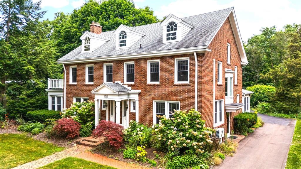 Located in the heart of Ann Arbor's beloved Burns Park neighborhood, this impressive 5+ bedroom, 5-bath home blends timeless character with thoughtful modern updates. Just a short stroll from the University of Michigan and downtown, this residence offers a rare combination of historic architecture, abundant space, and exceptional walkability. Step inside the grand entry and be transported -- original hardwood floors, solid wood doors, glass doorknobs, and finely crafted moldings create a warm and elegant welcome. The expansive living room, anchored by a striking period fireplace, flows seamlessly into a bright three-season room.A formal dining room sets the stage for memorable gatherings, while the renovated kitchen boasts high-end appliances, generous cabinetry, and a sun-drenched breakfast nook. A cozy sitting room just off the foyer, accessed through original French doors, makes an ideal home office, library, or reading lounge. Upstairs, four spacious bedrooms include a serene primary suite with a walk-in closet and a fully renovated bath. One of the bedrooms includes its own fireplace and balcony, perfect for work-from-home mornings or relaxing evenings. The updated hall bath features a built-in sauna and in-home laundry for ultimate convenience. The third floor offers remarkable versatility: bedrooms, a window-lined craft or sitting area, dedicated home offices, and a large space ready to be transformed into a home gym, or a creative retreat. Downstairs, the full basement includes a second laundry room, full bath, expansive rec room with fireplace, and plenty of storage. Outside, a winding paver path leads through beautifully landscaped gardens to two patios, ideal for entertaining or enjoying quiet moments. A charming, covered pergola leads to green space for play, while two detached garages offer parking for five vehicles and extra room for hobbies or workshop space. Located in one of Ann Arbor's most desirable neighborhoods, with easy access to top-rated schools, U-M campus, hospitals, the Arb, and vibran