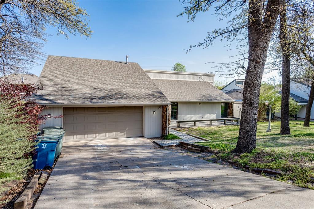 Architectural Gem nestled beneath a canopy of mature oaks — just steps from the beloved E.C. Hafer Park and with access to a private neighborhood pool! Bold board-and-batten siding, natural stone accent walls, and a dramatic two-story glass wall give this home a presence unlike anything in the neighborhood. Inside, soaring vaulted ceilings, an exposed wood beam, floor-to-ceiling stacked stone fireplace, and walls of glass create a great room that is truly breathtaking. A spacious bonus room off the great room is perfect for a billiards table, grand piano, or both. The reimagined kitchen features two-tone cabinetry, quartz countertops, a center island, subway tile backsplash, KitchenAid refrigerator, and industrial track lighting. A wet bar with custom shelving and a formal dining room with brass crystal chandelier complete the entertaining spaces. The primary suite offers vaulted ceilings, deck access, and a spa bath with clawfoot soaking tub, navy double vanity, stained glass accent window, and open marble walk-in shower. Secondary bedrooms feature new carpet, ceiling fans, and built-in closets, served by a double vanity bath with walk-in tile shower. A knotty pine loft with shiplap walls adds one-of-a-kind charm. Covered pergola deck, fenced backyard, storage shed, and zoned for Edmond Public Schools. A rare find — schedule your showing today!