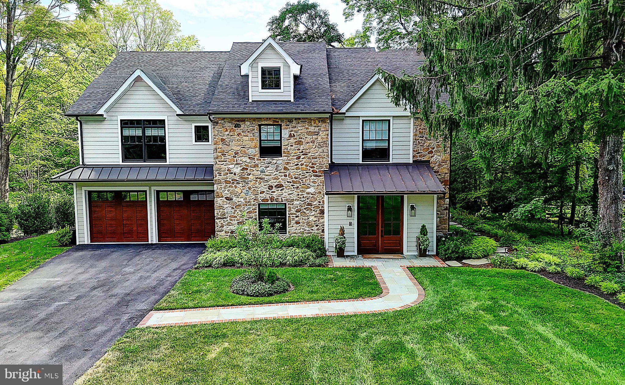 There are homes that are beautifully built, and then there are homes that possess a sense of place. Completed in 2022, this extraordinary residence was thoughtfully conceived to honor the character of its Villanova setting while embracing the scale, light and sophistication of contemporary living. Rather than erase the property's past, the builder preserved portions of the original stone facade and repurposed reclaimed timber throughout the interior. The result feels both established and fresh - Pennsylvania heritage reinterpreted through a modern lens. Step inside through a striking foyer grounded by original stone and brick flooring, where a dramatic reclaimed-timber arch immediately tells the home's story. Additional reclaimed wood appears as custom shelving, bringing warmth and authenticity to the clean architectural lines. Beyond, soaring ceilings, expansive windows and natural light create interiors that feel dramatic yet inviting. The living room is anchored by a gas fireplace, with a private study tucked just beyond. At the heart of the home is a beautifully executed gourmet kitchen designed for gathering. An oversized island, custom cabinetry, stone countertops, professional-style appliances and statement range hood are complemented by a walk-in pantry, wet bar and wine refrigeration. The kitchen opens to a breathtaking great room, where a soaring cathedral ceiling and dramatic wall of windows frame the landscape and blur the line between indoors and out. Upstairs, the primary suite feels like a private retreat, with a cathedral ceiling, covered balcony overlooking the grounds, two walk-in closets and a spa-inspired bath with soaking tub and separate shower. Two additional bedrooms each enjoy their own private en-suite baths. A fourth bedroom, currently transformed into a personal gym, offers wonderful flexibility. Directly accessible from the primary suite, the fifth bedroom is currently styled as a sitting room and, with generous closets, is ideal as a nursery, private lounge or second office. A beautifully tiled hall bath with double vanity and walk-in shower, plus second-floor laundry, complete the level. The finished walkout lower level shifts the mood entirely - an immersive entertainment space with custom wet bar, wine cooler, chalkboard wall, carefully planned lighting, powder room and direct access to the backyard. Extensive storage, a waterproofed crawlspace and separate utility room with reverse-osmosis water treatment add function behind the scenes. Outside, the grounds have been transformed into a private sanctuary. Stone walkways meander through lush landscaping to a patio with a motorized cover and integrated lighting. A separate picnic area creates another place to gather, while a secluded hammock retreat beneath mature trees offers a wonderfully tranquil place to read, unwind or simply enjoy the surroundings. Thoughtful privacy plantings and an invisible electric pet fence complete the setting. And throughout, technology is seamlessly integrated rather than seen. This is a fully connected smart home, with smart lighting and a Sono sound system extending throughout both the interior and exterior, allowing lighting and music to set the atmosphere from room to room and into the gardens. Dual HVAC systems, a generator, reverse-osmosis water treatment and an EV charging station further enhance everyday living. What distinguishes this home is the juxtaposition of old stone and new architecture, reclaimed timber and refined finishes, soaring spaces and intimate retreats, sophisticated technology and tranquil nature. It is a home designed not simply to impress, but to be lived in beautifully. Some of the Interior & exterior furnishing are available for purchase.