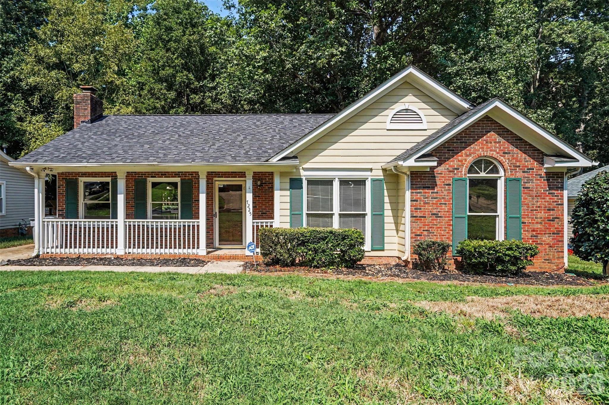 Welcome to 7225 McTeal Place, a charming single-story home in Charlotte’s Spring Crossing neighborhood offering a spacious 0.35-acre setting, inviting front porch, and a backyard surrounded by mature trees. Inside, an open and airy layout is enhanced by vaulted ceilings, warm flooring, and a striking brick fireplace that creates a natural focal point in the living room. The adjoining dining area features sliding glass doors that bring in plenty of natural light and provide an easy transition to the expansive rear deck, making the layout ideal for everyday living and entertaining.The kitchen offers crisp white cabinetry and generous workspace, while three bedrooms provide comfortable accommodations and flexibility for guests, a home office, or additional living space. The primary bedroom features a vaulted ceiling and walk-in closet, and the home includes two full baths. Outside, the large deck overlooks a wooded backyard with plenty of room to relax, garden, entertain, or create your own outdoor retreat. With no HOA, homeowners can enjoy added flexibility without neighborhood association dues. Conveniently situated in northeast Charlotte, Spring Crossing provides easy access to the University City area, UNC Charlotte, shopping and dining along the North Tryon Street corridor, nearby parks and greenways, and major routes including I-85 and I-485, offering convenient connections throughout the Charlotte area.