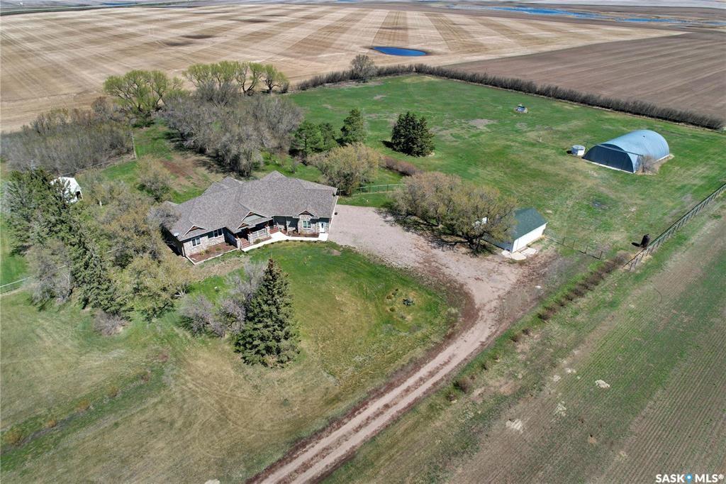 Set just 22 minutes from Saskatoon and moments from Delisle, this beautifully developed 13-acre property offers the perfect balance of privacy, space, and accessibility.  Built in 2020, this custom bungalow delivers over 5,000 sq ft of finished living space with 5 bedrooms, 4 bathrooms, and a triple attached heated garage. Designed with both function and comfort in mind, the home features vaulted ceilings, expansive windows, and two propane fireplaces that anchor the main living areas.  The kitchen is built for everyday living and entertaining, complete with a large quartzite island, custom cabinetry, walk-in pantry, and JennAir appliances. It opens seamlessly to the main living space, creating a bright and welcoming central hub.  The primary suite offers a private retreat with a walk-in closet, spa-inspired ensuite, and direct access to the rear deck. A fully developed basement adds exceptional flexibility, featuring additional bedrooms, a full bathroom, and generous space for recreation, fitness, or a home office.  Outdoors, the property is exceptionally well-equipped with a heated and insulated shop, a 42’ x 70’ finished Quonset with concrete floor, and a horse stable—ideal for hobby use, storage, or business opportunities.  Constructed to a high standard, the home includes triple-pane windows, ICF foundation, ROXUL insulation, durable 50-year shingles, in-floor heating, high-efficiency mechanical systems, and a two-stage septic system.  Located just outside Delisle with quick access to Highway 7, this property offers a rare combination of modern construction, usable land, and versatile outbuildings in a highly desirable location. Detailed feature sheets are available for a complete overview of this exceptional home.