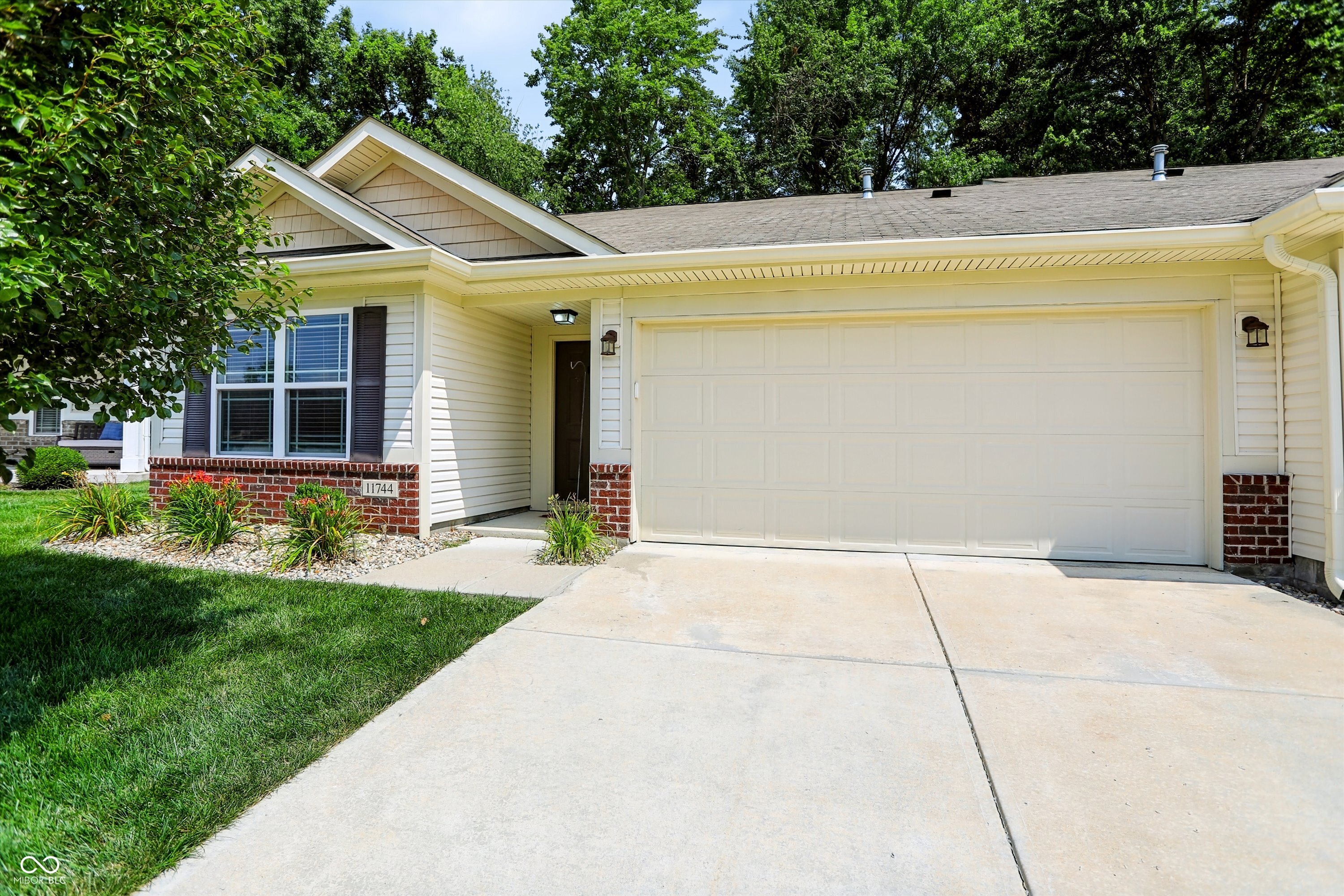 Welcome home to maintenance-free living at its finest in the highly desirable Whispering Woods community of Fishers. This immaculate, move-in-ready three-bedroom, two-bathroom condo welcomes you with new paint, new carpet, a warm, neutral color palette throughout and an exceptionally spacious open-concept floor plan. The bright living and dining areas flow seamlessly into a massive kitchen, boasting abundant counter space and cabinetry that will delight any home chef. Just off the kitchen, a highly functional laundry and mudroom area-complete with a new water heater-provides convenient daily access to the attached two-car garage.  The generous primary suite serves as a private retreat, featuring an ensuite bath with a double vanity, a walk-in shower, and an expansive walk-in closet. Two additional spacious bedrooms and a pristine full guest bath offer plenty of flexibility for family, guests, or a quiet home office. Step outside to your private backyard oasis, where a charming patio and gorgeous pergola await your morning coffee or evening relaxation.  Situated in the top-rated Hamilton Southeastern School District, this home is tucked away off East 126th Street, putting you just minutes from Billericay Park, Brooks School Park, and the sparkling waters of Geist Reservoir. Grocery runs to Fresh Thyme, dinners at Ale Emporium, and daily commutes are an absolute breeze with fast, easy access to State Road 37 and I-69. This is the perfect blend of style, comfort, and lock-and-leave convenience.