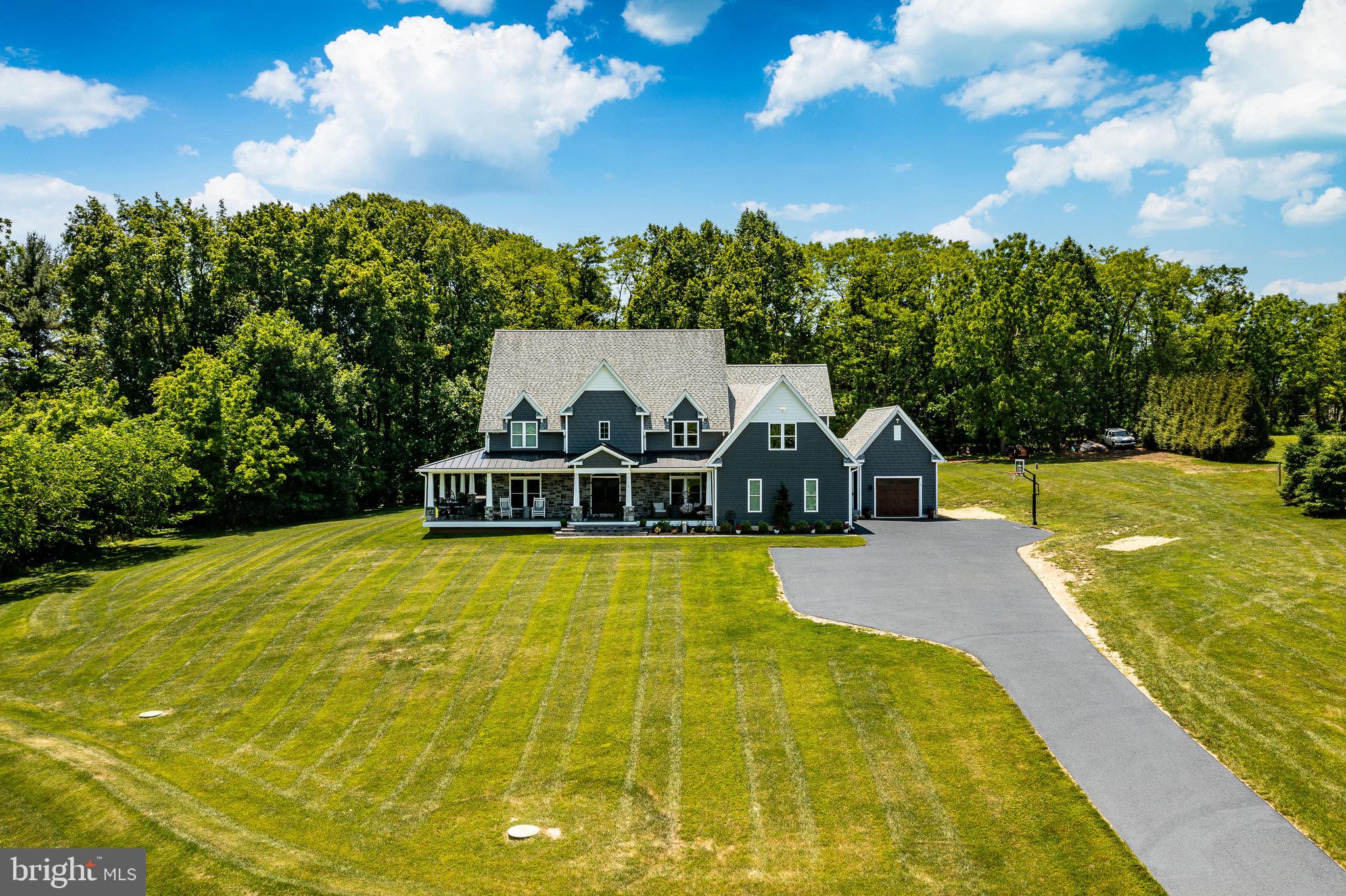 Situated on a breathtaking 2.47-acre homesite surrounded by mature trees, this extraordinary custom-built residence offers over 6,000 sq ft of thoughtfully designed living space, including a beautifully finished lower level. Built in 2019, this one-of-a-kind home combines striking Craftsman architecture, exceptional craftsmanship, and luxury finishes throughout.An oversized driveway welcomes you to the home's impressive exterior, where stone accents, shaker siding, and a sprawling wraparound front porch create unforgettable curb appeal. Offering two separate 2-car garages +extensive parking, the property delivers both functionality +estate-like presence.Inside, a dramatic two-story foyer showcases a curved staircase with stained hardwood treads + wrought-iron railings, setting the tone for the custom details found throughout. Antique doors, extensive millwork,+handcrafted finishes elevate every space.Designed for today's lifestyle, the main level features a dedicated office wing with 2 private offices, a spacious mudroom with custom built-ins, and elegant entertaining spaces. The formal dining room impresses with a coffered ceiling, custom wine storage, and a built-in quartz serving station.At the heart of the home, the chef's kitchen was designed to gather family +friends. Highlights include white+ gray shaker cabinetry, a massive 10-foot island topped with 3-inch-thick Carrara marble, Viking professional appliances, quartz countertops, built-in wine storage, and an incredible 10' x 8' walk-in pantry. Authentic barn beams, a vaulted shiplap ceiling, built-in speakers, and a stunning wood-burning stone fireplace create warmth+ character, while oversized windows and transoms fill the space with natural light.The adjoining family room is anchored by a floor-to-ceiling stone gas fireplace+ walls of windows overlooking the scenic property, creating a comfortable yet sophisticated gathering space.Upstairs, the luxurious owner's retreat serves as a private sanctuary featuring a tray ceiling, a custom accent wall, French doors opening to a Juliet balcony, and a spa-inspired bathroom finished in Carrara marble. Enjoy dual floating vanities, a freestanding soaking tub, oversized walk-in shower with rain head + body jets, + a custom walk-in closet with built-ins. 4 additional bedrooms, 2 full baths, and a spacious laundry room with double appliances complete the upper level.The finished lower level adds approximately 1,280 sq ft of additional living space and was designed with entertaining in mind. Features include a home theater area with built-in speakers, custom wet bar, a speak-easy style wine room, full bath, and a versatile flex space currently used as a gym that could easily be converted into a 6th bedroom, guest suite, or hobby room.Additional upgrades include 2x6 construction, a hybrid energy-efficient heating system, built-in speakers throughout, propane service, private well +septic, abundant storage, and attic storage above the tandem garage bay.This home is in the Downingtown school district with STEM and a short walk to Applecross Country Club. Take advantage of the amenities without paying the HOA!