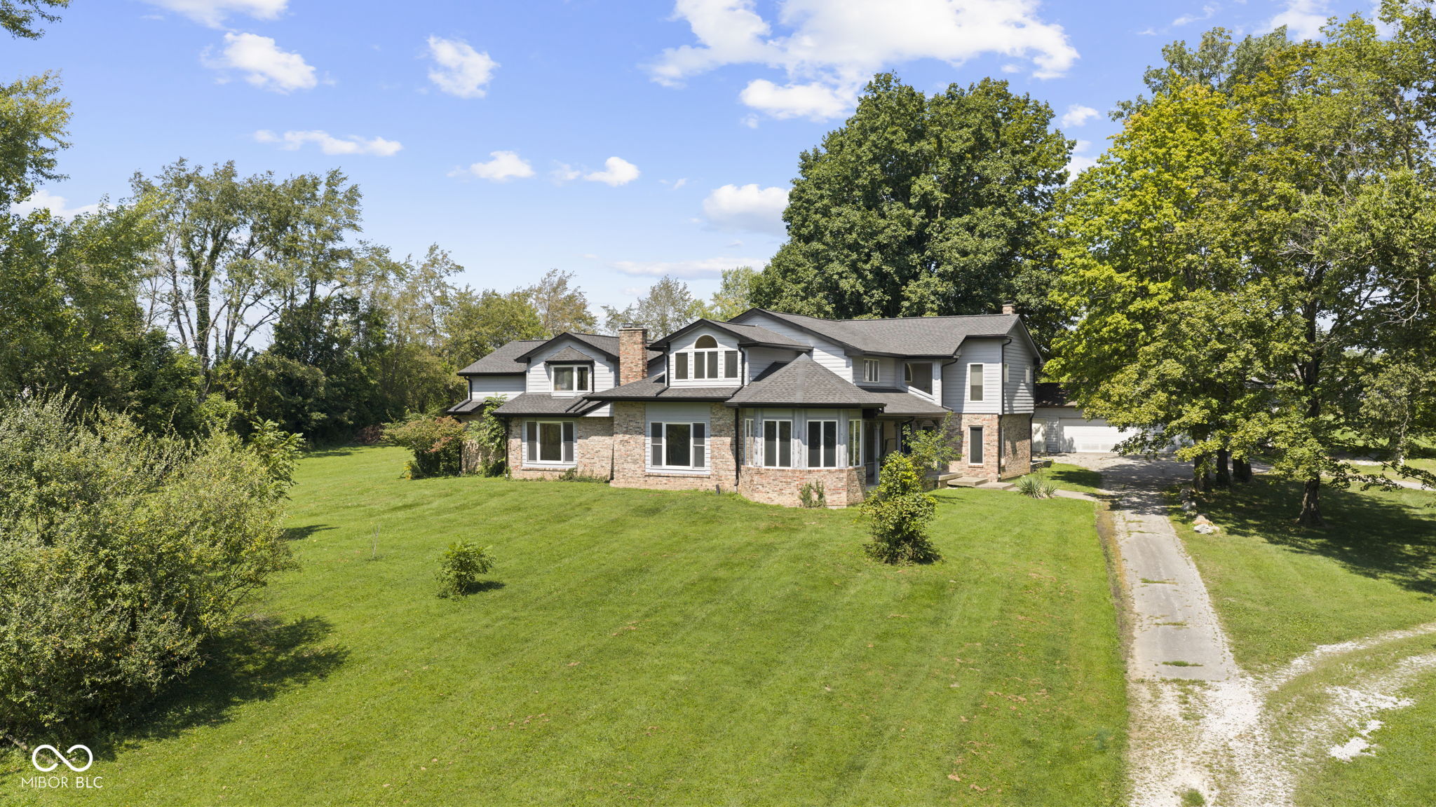 This massive 6,067-square-foot custom country estate home is beautifully situated off a long driveway on 4.10 peaceful acres just outside of Greencastle. Spacious and distinctive, this exceptional 5-bedroom, 3.5-bath home offers an incredible amount of living space, privacy, and versatility. The home features an amazing octagonal 4-seasons room at the front, complete with double glass doors leading to a covered side porch. Inside, you'll find generously sized rooms throughout, including a Living Room, Family Room, and an impressive upstairs Great Room. The heart of the home is the spacious kitchen, featuring a large center island, pantry, and stainless-steel stove, refrigerator, dishwasher, and microwave-all included. A large back deck is located off the combined Kithcen/Dining/Living Room area. A convenient Home Office, upstairs Loft, and huge Laundry Room/Mud Room with utility sink add even more functionality. Washer and dryer are included, as well.  Warm up on chilly evenings beside one of the home's 3 woodburning fireplaces, located in the Living Room, Family Room, and Primary Bedroom.  The Primary Bedroom Suite is truly spectacular, offering an incredible private retreat. The suite includes a fireplace, separate sitting room, spacious 10x10 bathroom with granite countertop vanity, soaking tub, oversized walk-in shower with seat, and a walk-in closet that dreams are made of.  The suite also opens directly to a rear Sun Room overlooking the expansive backyard and surrounding woods.  Upstairs, you'll find a second Primary Bedroom Suite with its own full bathroom, along with three additional bedrooms sharing another full bathroom. The upstairs Great Room and Loft create even more flexible living space for family, guests, hobbies, recreation, or entertaining.  The 1,700-square-foot 3-car Garage/Pole Barn with Lean-to can't be beat and give you all the space you need for parking and storage.  Properties like this one are once-in-a-lifetime.  Come and take a look.