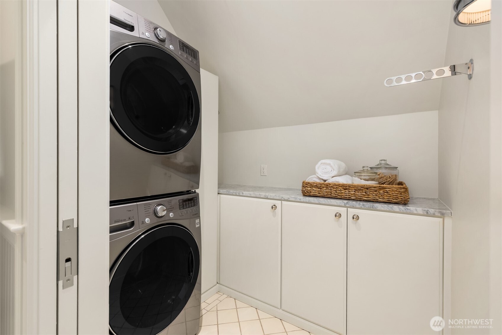 Convenient laundry room featuring a stacked washer/dryer and marble countertop storage.