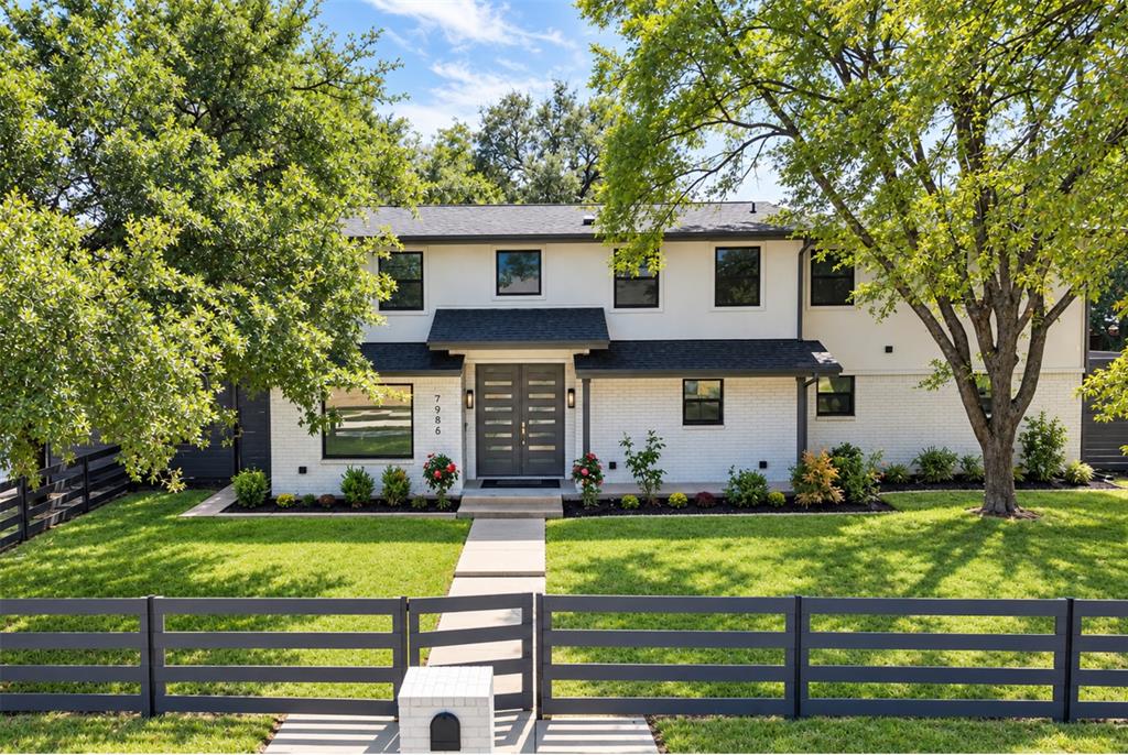 Picture coming home to tree-lined streets, a light-filled open floor plan and a backyard made for gathering. This home offers 5 bedrooms and 4.5 baths in the established Spring Creek neighborhood of North Dallas. The crisp white exterior, black framed windows and sleek horizontal fence create instant curb appeal. Inside, the foyer opens to a light-filled floor plan with wood-look floors, designer lighting and a striking staircase with modern metal railings. The living room is anchored by a fireplace set against a bold navy accent wall with lit built-in shelving, and it flows easily into the dining area and kitchen. The kitchen is made for gathering, featuring a large quartz island with seating, white shaker cabinetry, glass-front uppers, a statement range hood, stainless steel appliances, a gas cooktop and a built-in beverage fridge. A main level bedroom, a private office and a convenient half bath add everyday flexibility, while the laundry room keeps things organized. Upstairs, a spacious family room overlooks the open space below, perfect for movie nights, a game room or a play area. The primary suite is a true retreat with generous walk-in closets and a spa-style bath offering a freestanding soaking tub, a frameless glass walk-in shower and dual vanities. The additional bedrooms are bright and roomy, each with easy access to well-appointed baths. Step outside to a huge, private backyard shaded by towering oaks. The covered gazebo patio is ideal for outdoor dining and relaxing, and there is plenty of green space to play, garden or entertain. A long driveway leads to a rear-entry garage with a modern glass door and room for extra parking. All of this sits in a quiet, tree-lined neighborhood with quick access to major highways, shopping, dining and everything North Dallas has to offer.