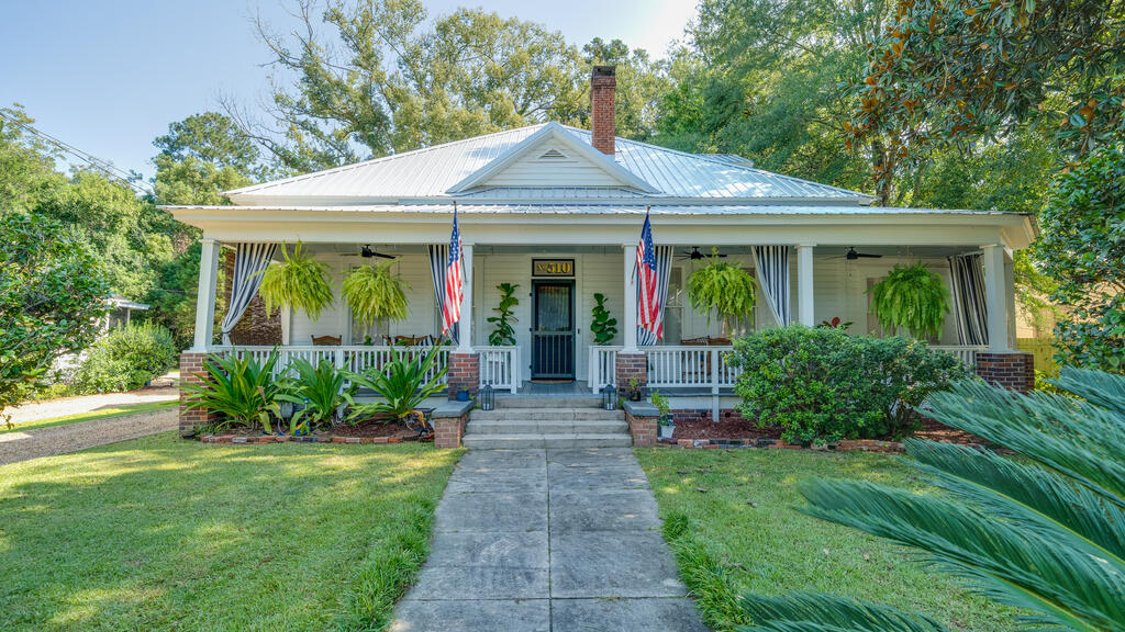 D.F. Scoggins House - Meticulously updated Victorian-era bungalow reimagined for contemporary lifestyle. Situated within Thomasville on a sprawling 0.61-acre lot, this 1916 jewel stands as a celebration of preservation, as honored with a restoration award from Thomasville Landmarks.  Enjoy slow afternoons and evenings on the expansive front porch.  Inside, pure southern magic! Soaring ceilings, original hardwood floors, pocket doors, and natural light create an atmosphere of opulence. Hand-hewn antique beams—salvaged from a local historic bridge—add rugged historic warmth to the dining room. The French bistro-inspired chef's kitchen is certain to inspire delectable meals, or at least the best cup of coffee. The versatile floorplan includes a rear "den" or keeping room, Two main level bedrooms enjoy en-suite bathrooms, as well as the spectacular 600+ sf loft retreat. The home beautifully balances romantic historic soul with top-tier functionality.  KEY HEIRLOOM FEATURES: PRIME LOCATION: Exceptional walkability to downtown "The Bricks"—perfect for dynamic neighborhood strolls or quick golf cart rides to local dining and shopping. Just one block to the Lapham-Patterson House Historic Site and Thomasville History Center.  HISTORIC AUTHENTICITY: Brand new, nostalgic silver tin roof protecting meticulously restored original architectural details and brick chimney. VERSATILE 3 en suite bedroom LAYOUT THE UPPER SANCTUARY: Crowned by exposed beams, this massive 3rd bedroom serves as a dramatic, flexible retreat—ideal for an art studio, wellness space, or private office. EXTERIOR ASSETS: Generous 0.61-acre lot featuring a detached two-car carport and expansive backyard. A property of this caliber must be experienced in person. Schedule your private viewing today to discover the rare privilege of calling this Thomasville heirloom your home.