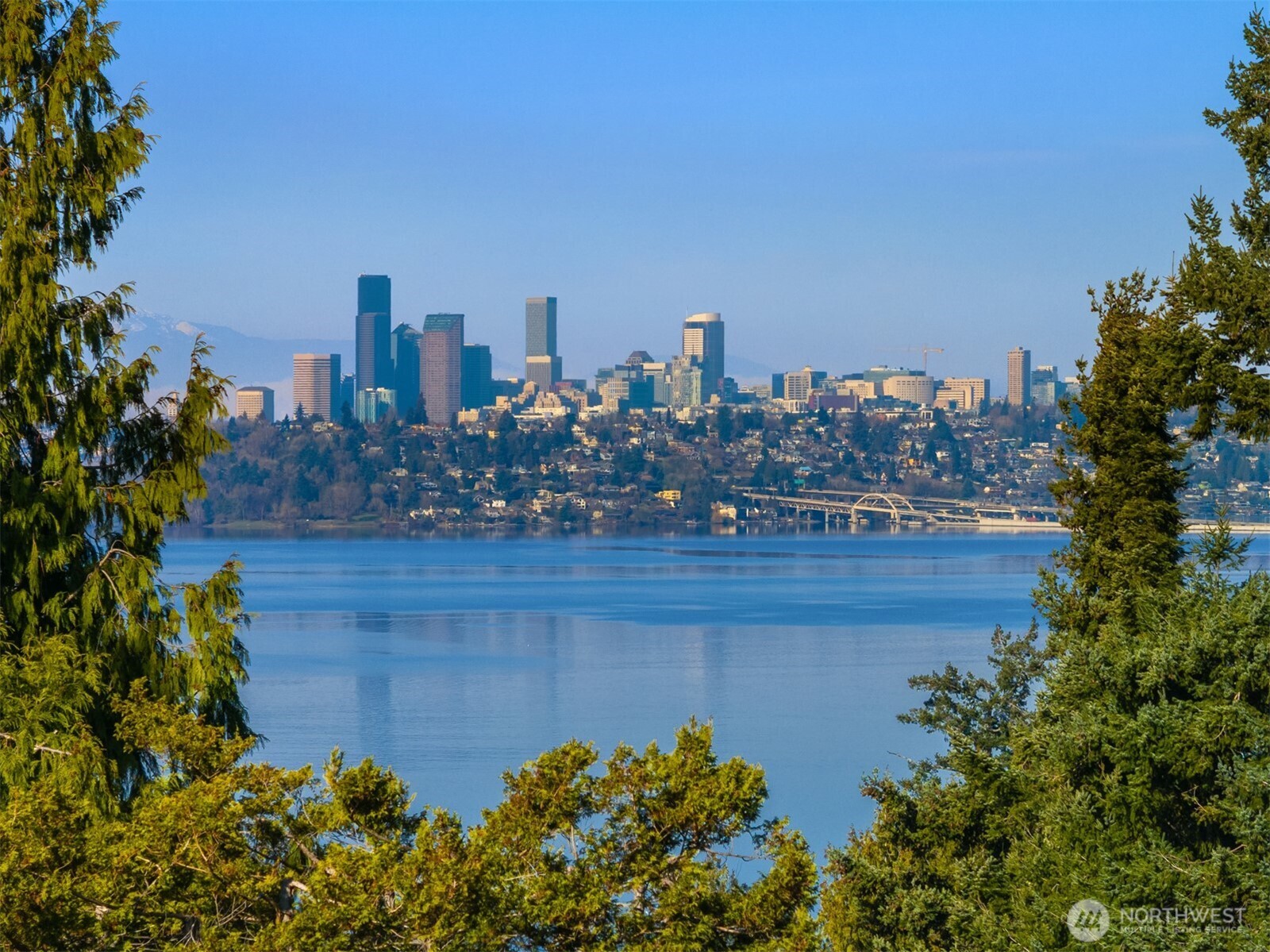 Nestled in the heart of Mercer Island, this mid-island residence captures the very essence of Pacific Northwest living, pairing sweeping west-facing sunset views with fresh, thoughtful updates throughout. A private courtyard entrance creates a warm and welcoming arrival experience, offering both seclusion and architectural charm before stepping inside. The main living areas and primary suite are ideally positioned to showcase vistas of Lake Washington, the Downtown Seattle skyline, and the majestic Olympic Mountains. Vaulted ceilings elevate the gathering room, where an open-concept kitchen flows effortlessly into light-filled spaces designed for both daily comfort and refined entertaining, while multiple decks seamlessly extend living spaces outdoors. Fresh interior paint, new carpeting, and beautifully updated kitchen and primary bath create a truly move-in ready experience. Beyond the main living spaces, the home continues to impress with a dedicated view studio providing inspiring space for artistic pursuits or a private office and a detached ADU offering exceptional flexibility for guest accommodations or revenue potential.