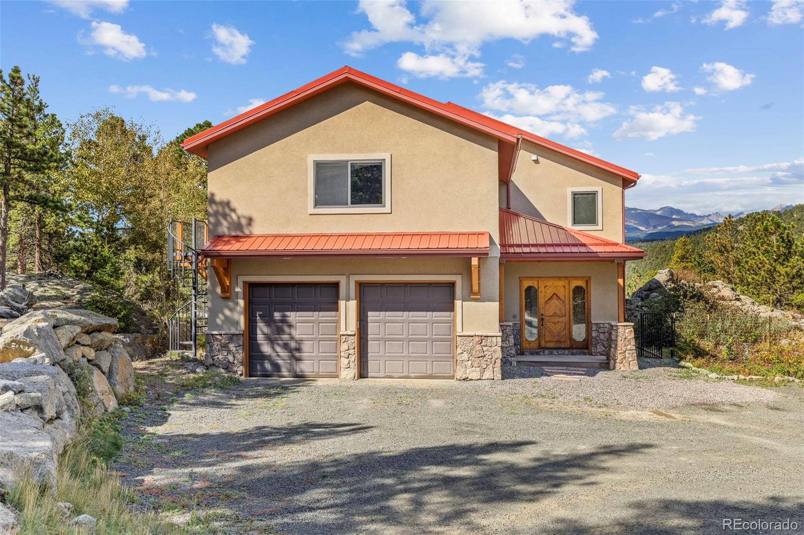 Located at the end of the road, this custom stucco home, built in 2007, occupies 7 private acres in a coveted neighborhood just minutes from Nederland, with 3 sides adjoining National Forest. Framed by dramatic rock outcroppings and sweeping snowcapped Indian Peaks views, this exceptional property offers refined craftsmanship, seclusion and direct access to nature. A private drive leads to a level parking area and oversized 2-car garage. Inside, the tiled foyer opens to an inviting open-concept main level designed for living and entertaining. The well-appointed kitchen features granite counters, a 4-person bar, stainless appliances and an oversized pantry, while the adjacent dining and living areas showcase newly refinished hickory floors, tall ceilings and a wall of windows capturing the mountain panorama. Step outside to a spacious composite deck and flagstone patio that leads to a hot tub nestled against tumbled boulders. A dedicated office with Murphy bed offers flexibility as a 4th bedroom, while a half bath completes the main level. Upstairs, 3 generous bedrooms accompany a massive rec room/flex space with balcony, views and a metal spiral staircase to the grounds. The primary suite is oriented toward the views and features an ensuite with soaking tub, separate shower and private balcony with spiral stairs to the deck. An owned solar system helps offset energy costs. A fenced yard provides space for pets or play, while rock outcroppings and a private trail system lead toward National Forest and miles of hiking from your doorstep. The basement offers potential for future finished space, with a finished laundry room already in place. A metal roof and new tankless water heater add to the home's enduring appeal. Just 10 minutes to Nederland and an easy, scenic commute to Boulder via the summer access road, this is a special mountain property with the quality, setting and timeless appeal to become a legacy home for generations.