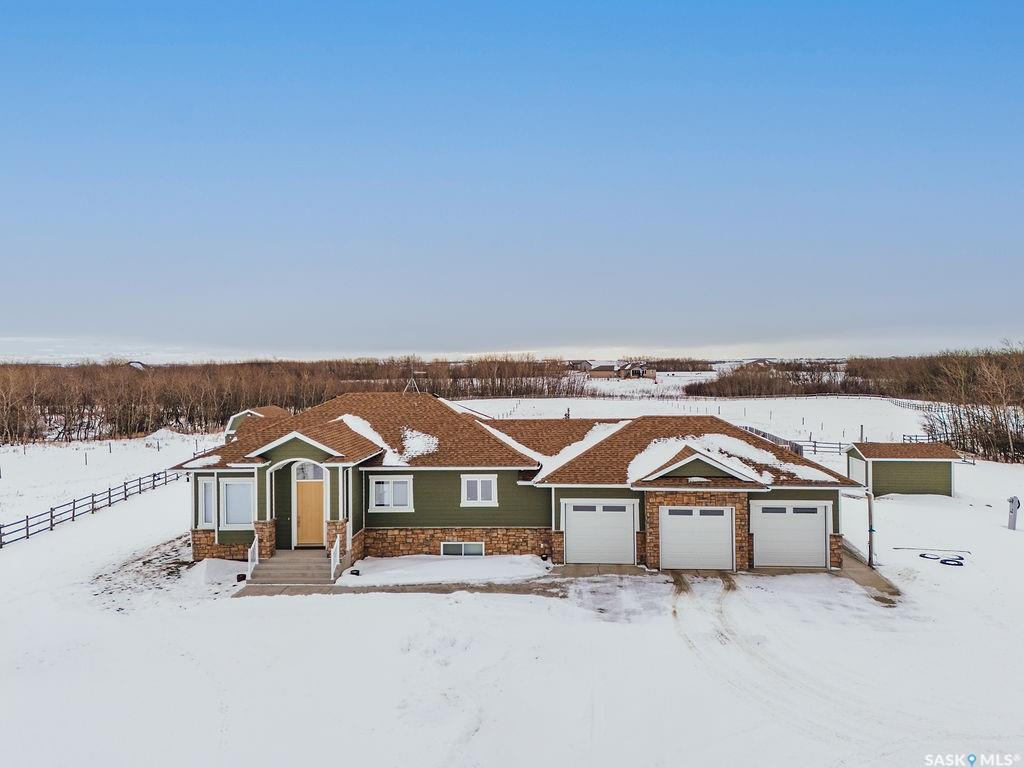 Welcome to 118 Louise Crescent in the coveted acreage community of Cherry Hills Estates,just 15 minutes from Saskatoon’s edge. This 1,502 sq. ft. executive bungalow is a stunning blend of modern design, smart functionality, and country charm. Step inside to discover a bright, open-concept main floor with an exceptional window package that floods the home with natural light. The spacious living room, dining area, and kitchen flow seamlessly under a vaulted ceiling, creating the perfect setting for entertaining or relaxing. The kitchen features quartz countertops, a corner pantry, roll-out drawers, stainless steal appliances. The dining room can easily seat a large extended family for holiday meals and the gas fireplace in the adjoining living room makes for cozy evenings. Hardwood runs throughout the main level, and a covered deck off the dining area allows for year-round BBQ. The primary suite is a lovely retreat, offering a large walk-in closet & an ensuite with a soaker tub beneath a privacy rain-glass window, heated floors, & a walk-in shower. A 2nd large bedroom (or office), another 4-piece bath, and a spacious mudroom/laundry room with built-in cabinetry, quartz countertops, and deep utility sink complete the main floor — all leading to an oversized triple-car garage with a separate workshop bay and a sunlit all-season greenhouse.The fully finished basement features a large family and games area, 2 more bedrooms, 4-piece bath, and a vented cold storage room perfect for preserves or wine. Outside, the 7.14 acre property is 3/4 fenced with treated rail fencing, hotwired, & divided into five paddocks with a 4-season watering bowl sourced by underground lines. Mature spruce trees border the property, and there’s a drive-in garden shed, an adorable matching horse barn, and 2 fully developed gardens with direct waterlines. Complete with central air, central vac, and window coverings, this Cherry Hills acreage offers comfort with country serenity — a truly rare find.