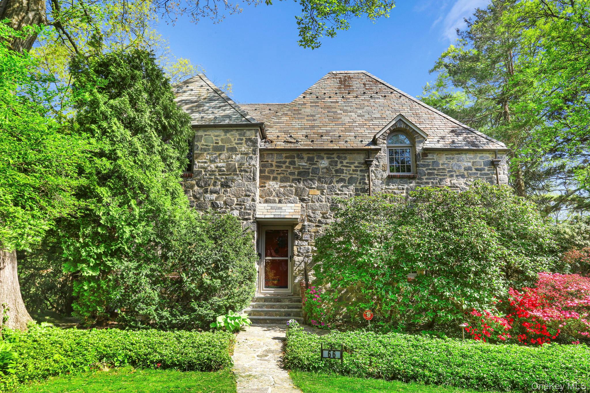 Welcome to this timeless 1926 stone and stucco Colonial, where classic architectural charm meets thoughtful modern updates. Set on a beautifully landscaped .18-acre lot, which provides lush views from every window,  this approximately 2,456 sq. ft. home offers exceptional craftsmanship, gracious living spaces, and a seamless blend of character and comfort...A welcoming foyer opens to a spacious living room with a wood-burning fireplace and an elegant dining room-perfect for entertaining. The updated kitchen features a heated floor, dinette area, pantry, and premium appliances, including a Wolf range, Bertazzoni refrigerator, and Bosch dishwasher. Upstairs, the home offers three generously sized bedrooms and two beautifully updated marble bathrooms, including a private primary suite. A unique highlight is the second-floor terrace off the third bedroom with murphy bed-ideal for relaxing or working from home with fresh air and privacy. The outdoor space is equally impressive, featuring a terraced garden with stone walls, walkways, and railings, along with a large stone back porch-perfect for gatherings. Additional features include a slate roof with copper gutters, central air, a full attic, and updated lower level with a two-car garage. Extensive recent updates (2022-2026) provide peace of mind, including a new boiler, Andersen windows, AC compressor sump pump, appliances, custom radiator covers, and more. The home also includes a radon mitigation system, updated electrical, and numerous safety enhancements. This home offers timeless appeal with modern convenience-truly move-in ready and just a 8 minute walk to the Hartsdale Train Station-37 Minutes to Manhattan.